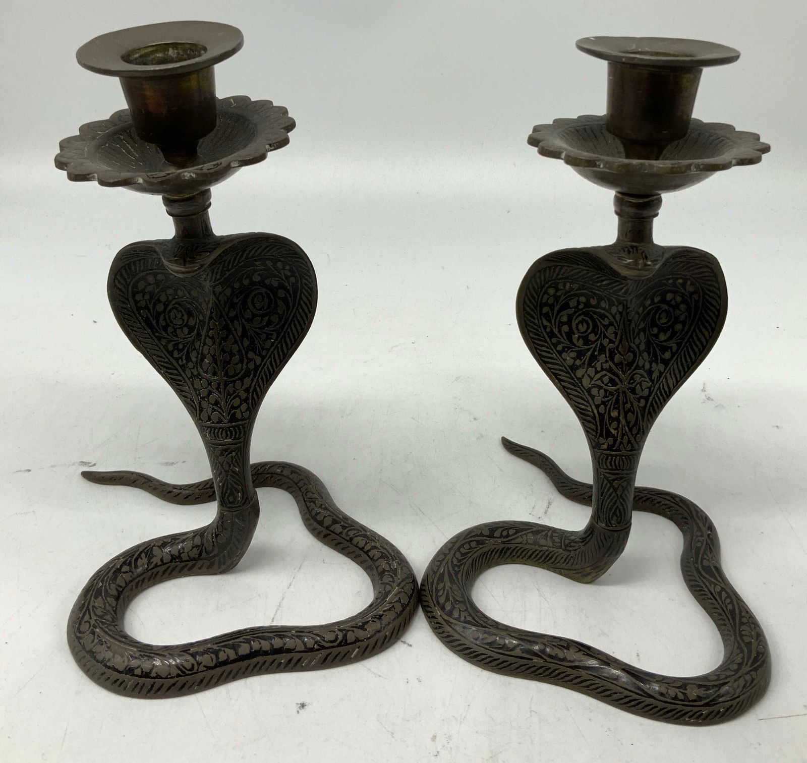 Vtg Pair Bronze Cobra Snake Candlesticks: Pair of bronze candlesticks shaped as cobra snakes. Cobras are in an upright position & feature intricate detailing. Head of cobras support a scalloped drip pan & candle cup. Surface wear consistent t
