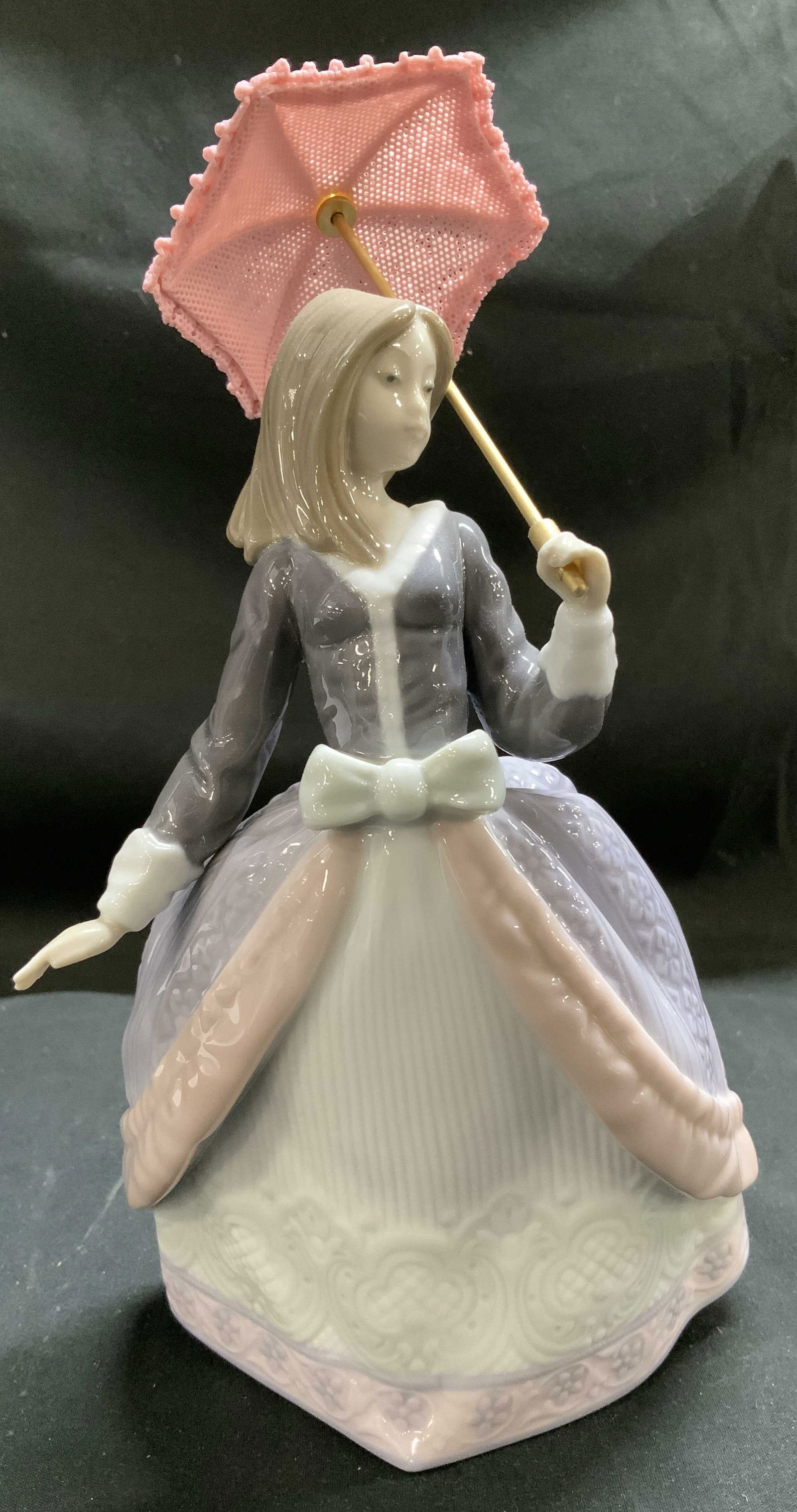 Lladro Girl W Pink Parasol Porcelain Fig SPAIN: Figurine depicts a girl in a long, elegant dress. Dress is lavender, pink & white toned w a white bow at the waist. Figurine is holding a pink parasol. Signed & marked on underside. Reads, LLADRO. HAN