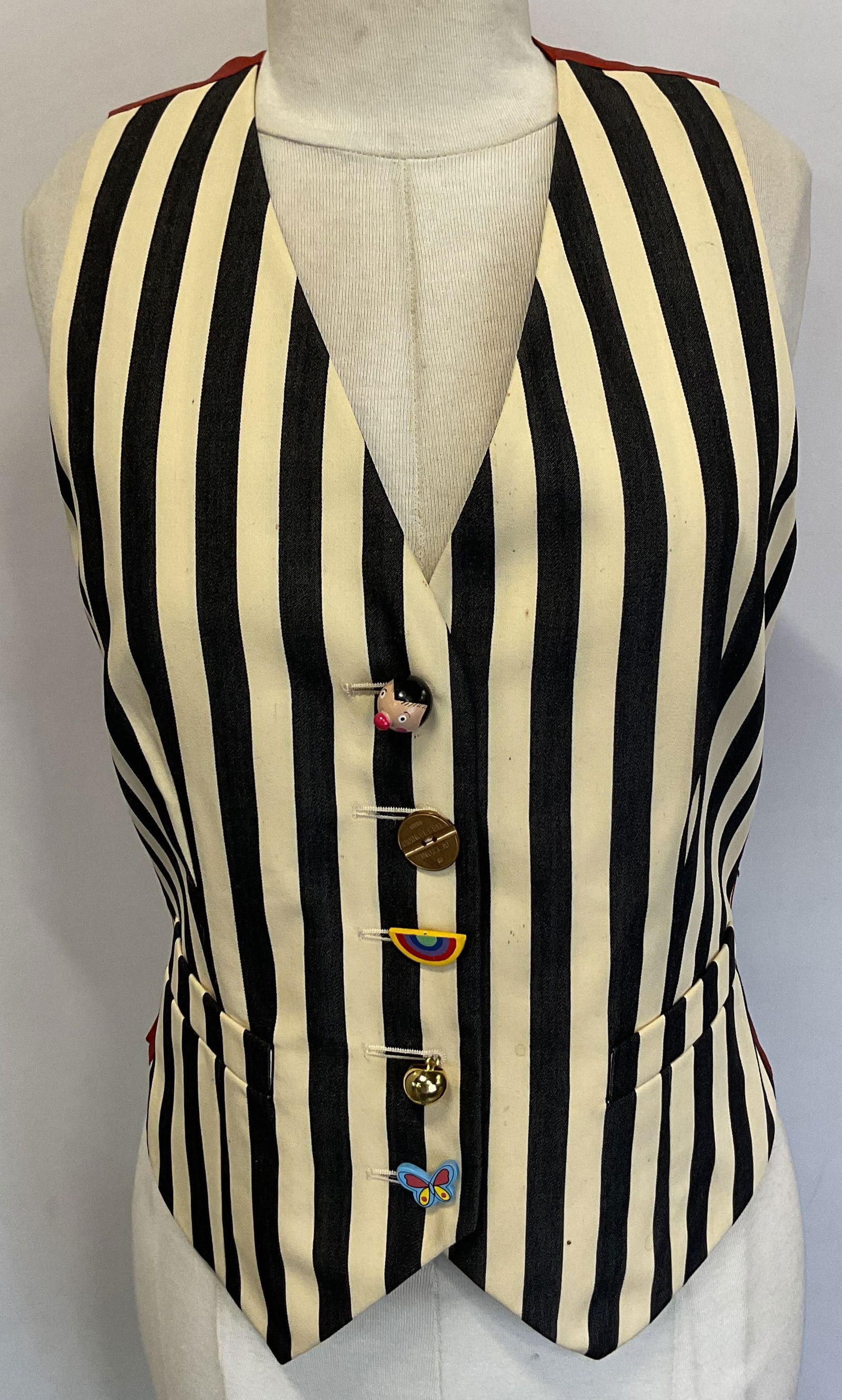 Cheap And Chic By Moschino Striped Vest Italy: Cheap and Chic by Moschino striped vest. Made in Italy. Size 8. Wool material. Red back with black and white striped pattern. Button like symbols including rainbow, butterfly, and more. Two front pock