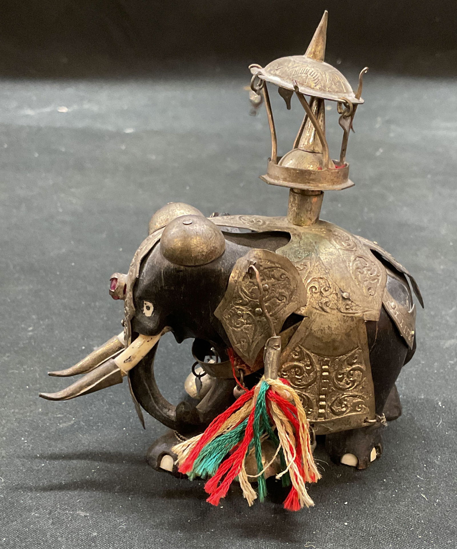 Antique Indian Processional Elephant Ruby Figurine: Antique Indian processional elephant figurine. Ebonized wood, bone, semiprecious stone (appears to be a ruby), and metal overlay. Measures approx 4 x 2 x 4.25 inches. Wear including patina, hairlines,