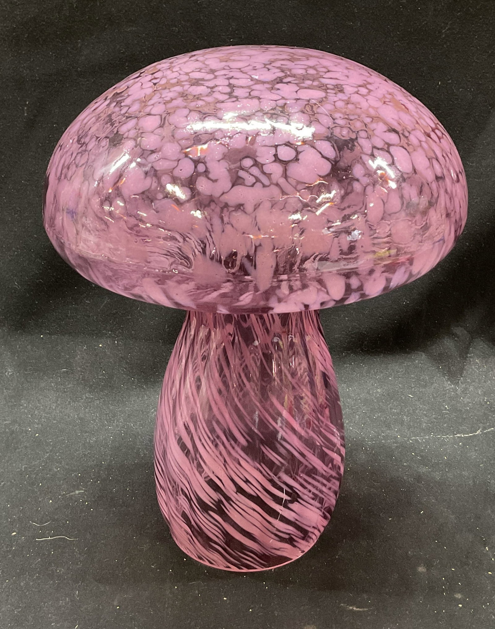 Hand Blown Art Glass Mushroom: Hand blown art glass mushroom. Wide and round cap. Crackled like pattern with pink and purple shades. Short and thick stem, ribbed texture. Swirl like design in pink and purple shades. Hollow on under