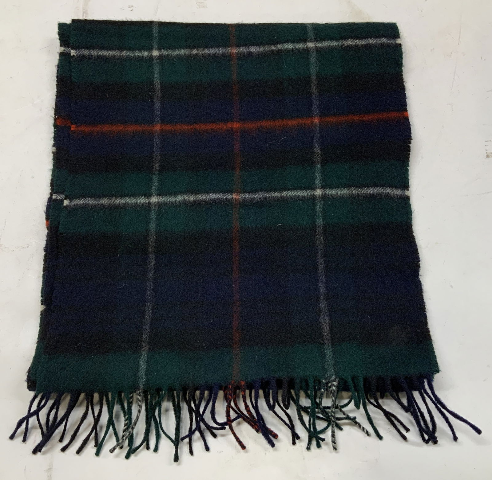 Jaeger Mackenzie Tartan Fringed Scarf SCOTLAND: Scarf is 70% cashmere & 30% wool. Scarf features a classic Mackenzie tartan pattern, in shades of navy, red, green & white. Signed & marked. Reads, JAEGER. LONDON. NEW YORK. PARIS. MACKENZIE. MADE IN