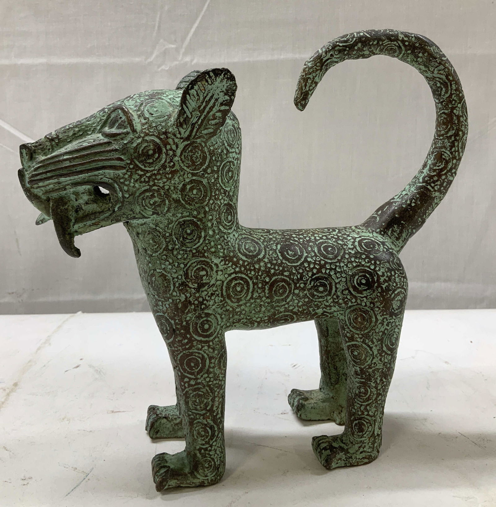 Vntg Standing Benin Bronze Leopard Figurine: Figurine appears to be bronze & features heavy green patina. Intricately detailed w swirling patterns covering entire body & textured teeth. Surface wear consistent to age, use & exposure. Measurement