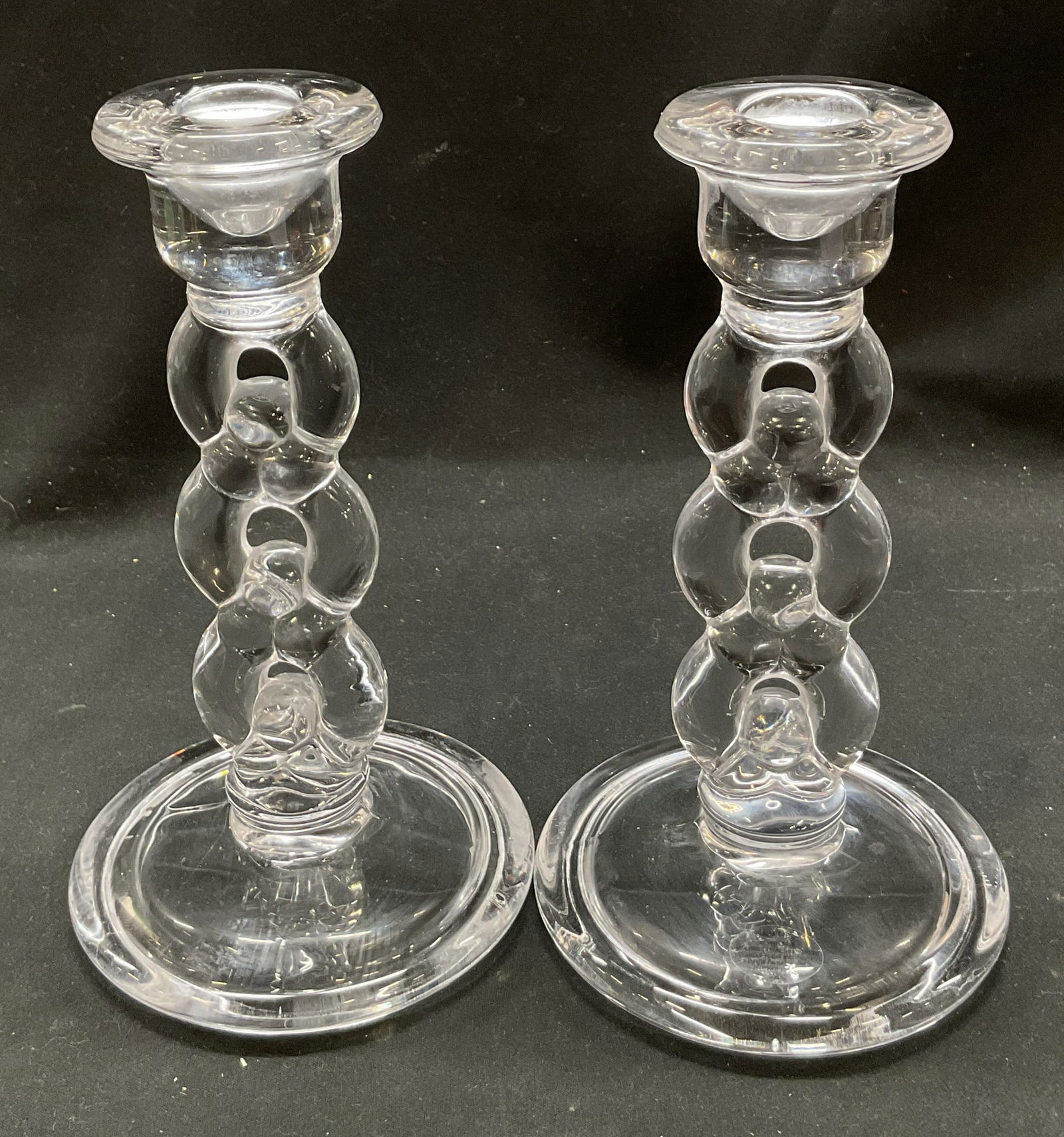 Pair Glass Chainlink Candlesticks: Pair of glass chainlink style candlesticks. Wide circular base. Interlocking rings design. Measures ht approx 7 inches base diameter approx 4 inches. Surface wear consistent with exposure. Candlestick