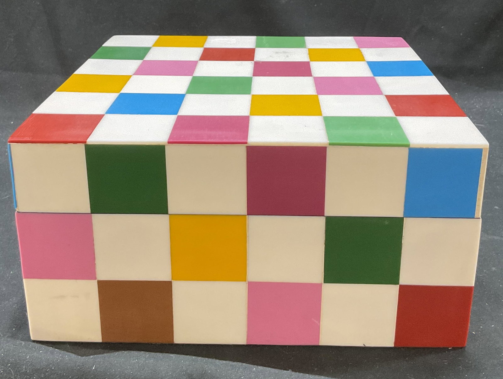 Tozai Home Faux Bone Checker Lidded Box India: Tozai Home faux bone checker patterned lidded box. Sticker adhered to underside, reads Handmade in India. Checker pattern with white, green, red, blue, pink, and yellow. Square shaped. Measures approx