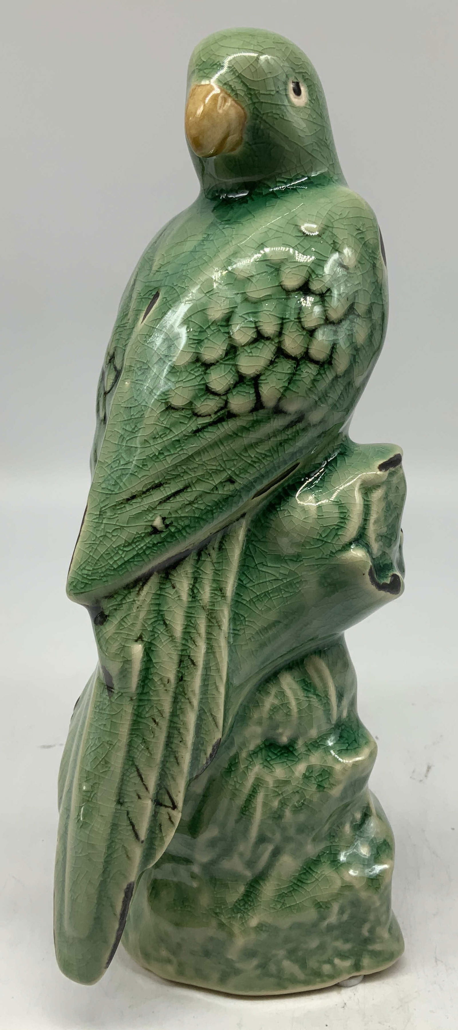 Tozai Home Green Glazed Ceramic Parrot: Parrot is perched on ceramic rock base. Green glazed finish w textured details on feathers. Glossy finish. Signed & marked on underside. Reads, TOZAI HOME. Surface wear consistent to age, use & exposu