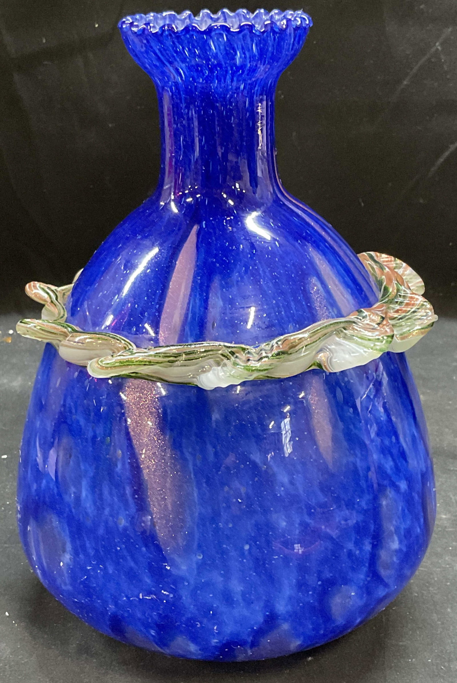 Hand Blown Blue Gold Fleck Art Glass Ruffle Vase: Hand blown art glass vase. Cobalt blue with gold fleck. Applied green ruffle. Measures approx 5.75 x 8.5 inches. Some scratching. Art glass vase, blue vase, gold fleck vase, ruffle vase, decorative ar