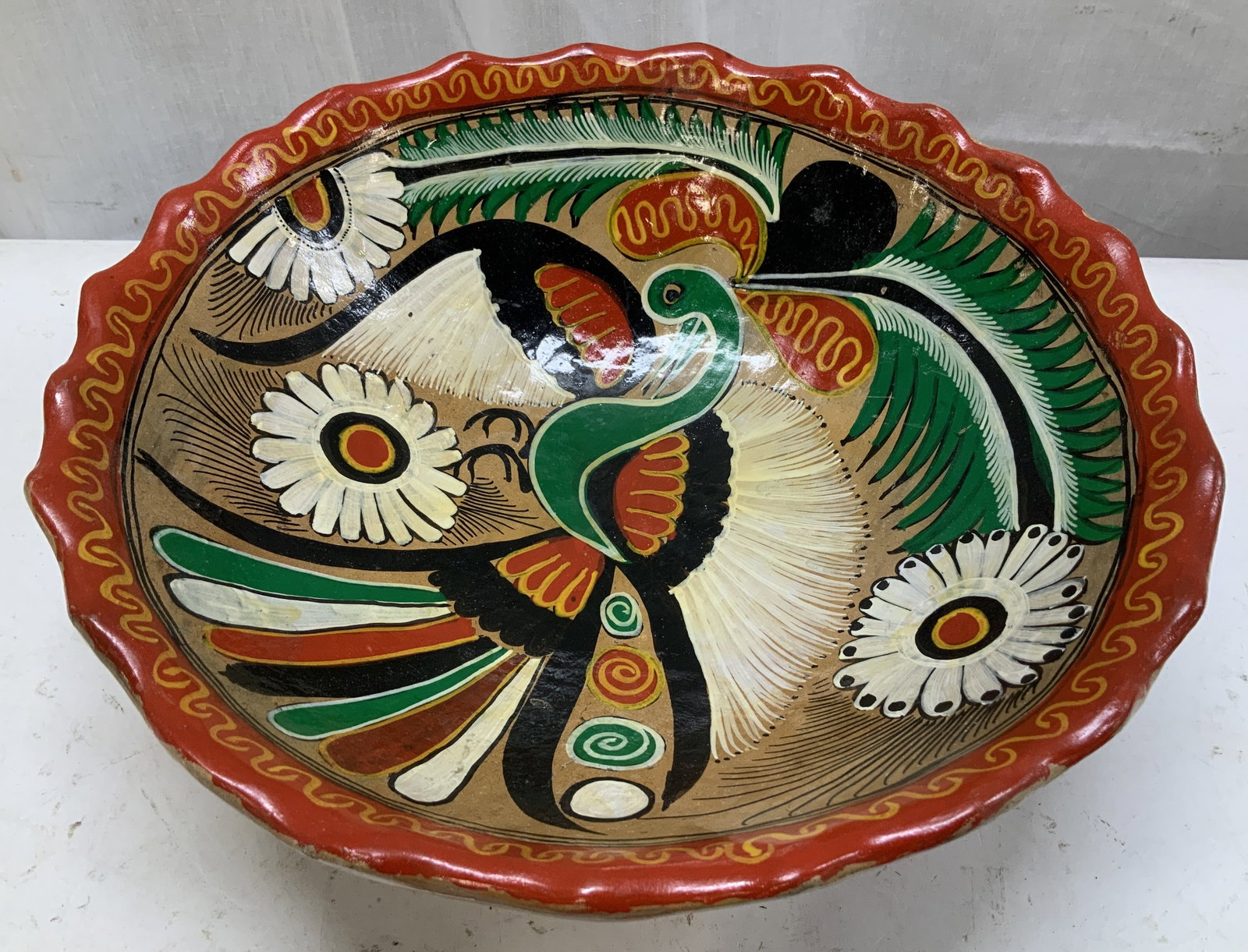 Hand Painted Talavera Style Bird Motif Deco Bowl: Hand-painted ceramic bowl featuring elaborate bird & floral motifs. Tones of green, red, black, yellow & white. Scalloped edge & 3 feet. Talavera style. Surface wear consistent to age, use & exposure.