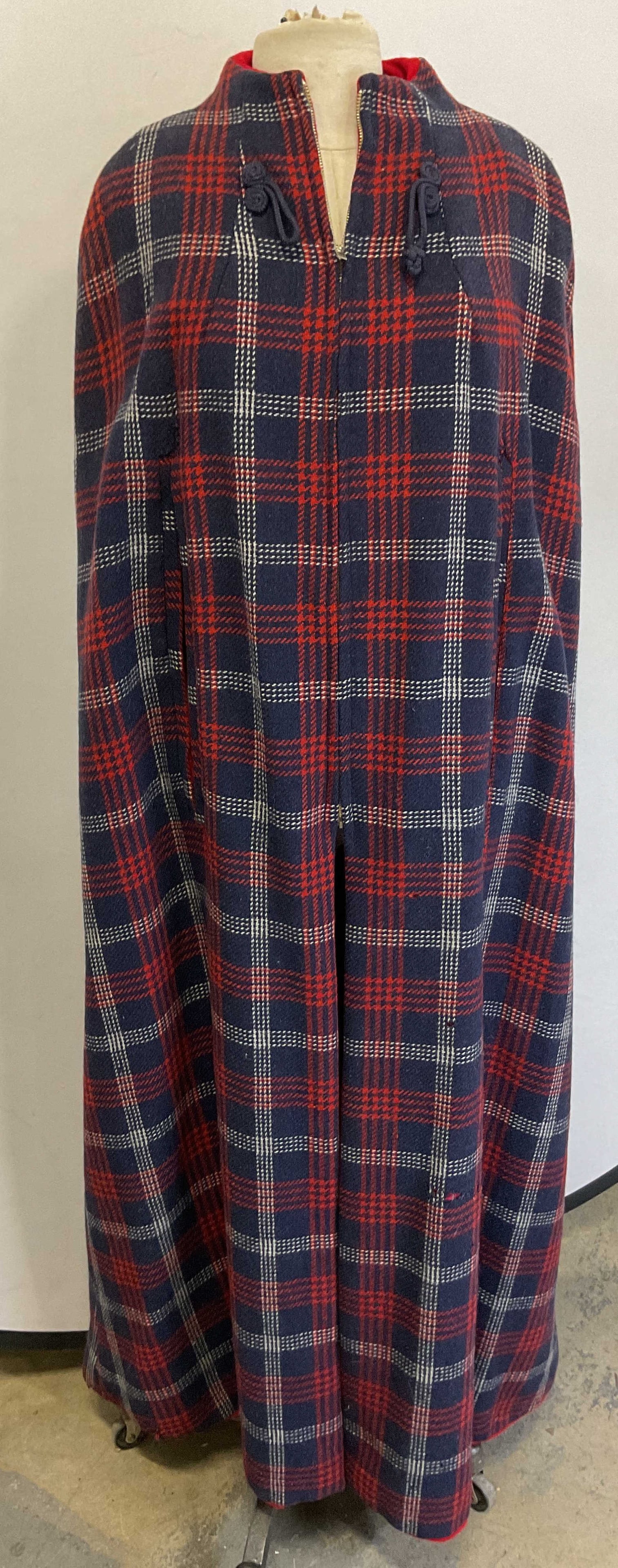 Vintage Red & Blue Plaid Cut Out Cape: Vintage red and blue plaid cape. Front zipper. Split seam cut outs on each side for arms. Plaid pattern in red, blue, and white. Swirl like accents. Collared. Split seam when zipped. Measures approx 2