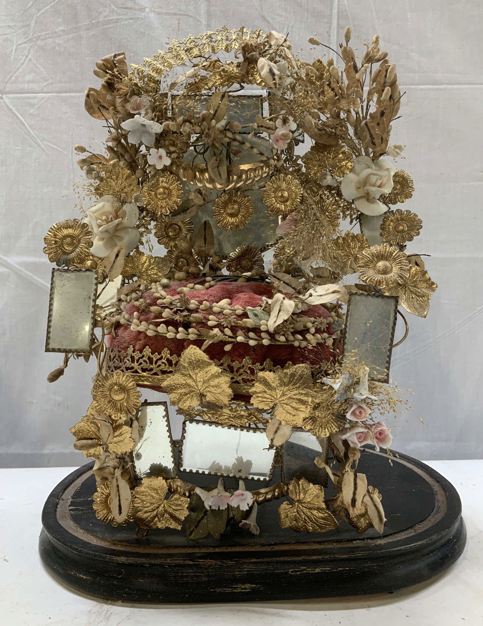 Antique French Globe De Mariee Wedding Dome: Features red velvet cushion surrounded by gilt metal floral mounts, mirrored plaques, porcelain & dried floral motifs. Piece is set on a round wooden base. Surface wear consistent to age, use & exposu