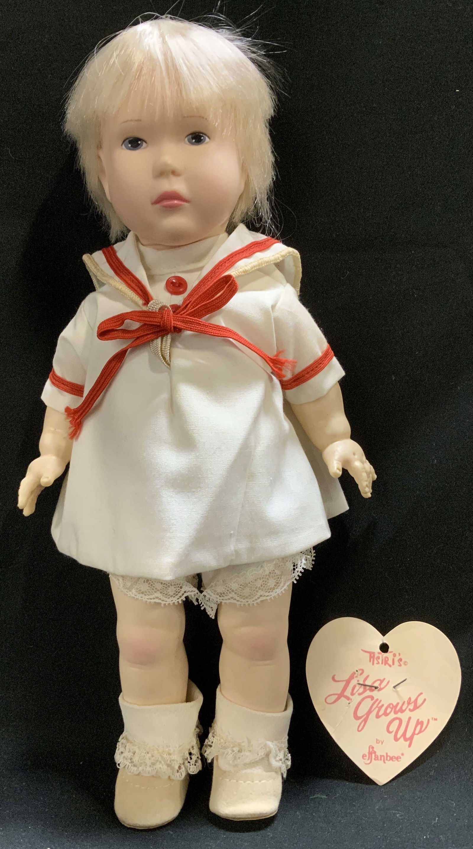 1980 Effanbee Astris Lisa Grows Up Sailor Doll: Vintage doll is wearing a white sailor-style dress w red ribbon tie, lace trimmed undies, socks & shoes. Comes with Effanbee heart tag. Signed & marked on back of doll. Reads, EFFANBEE 1980. Surface w