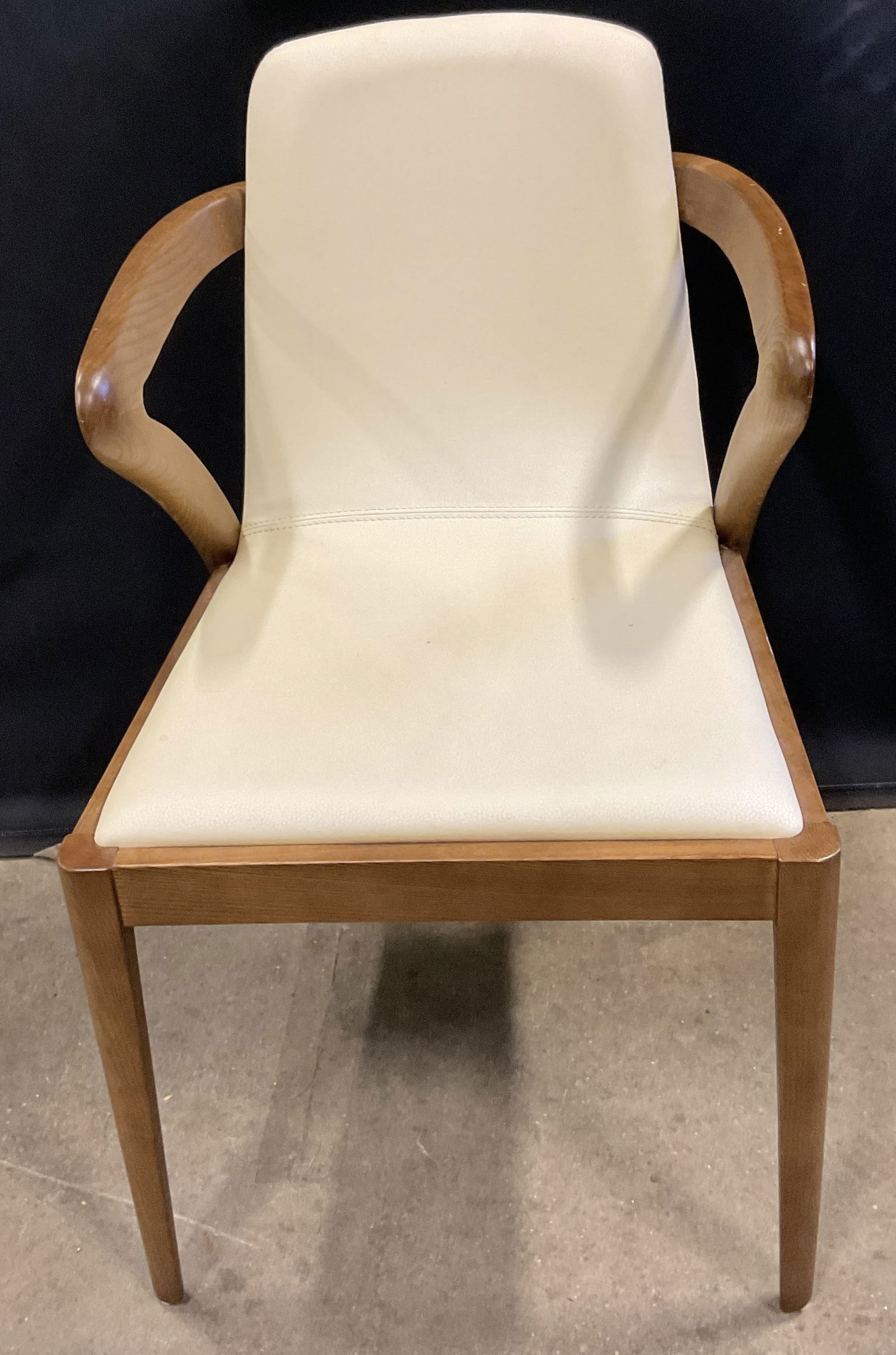 White Faux Leather Upholstered Wood Armchair: White faux leather upholstered armchair. Modernist style curved arms. Measures approx 19 x 19 x 32 inches. Some scratching. Modern style chair, armchair, wood chair, faux leather chair, upholstered ch