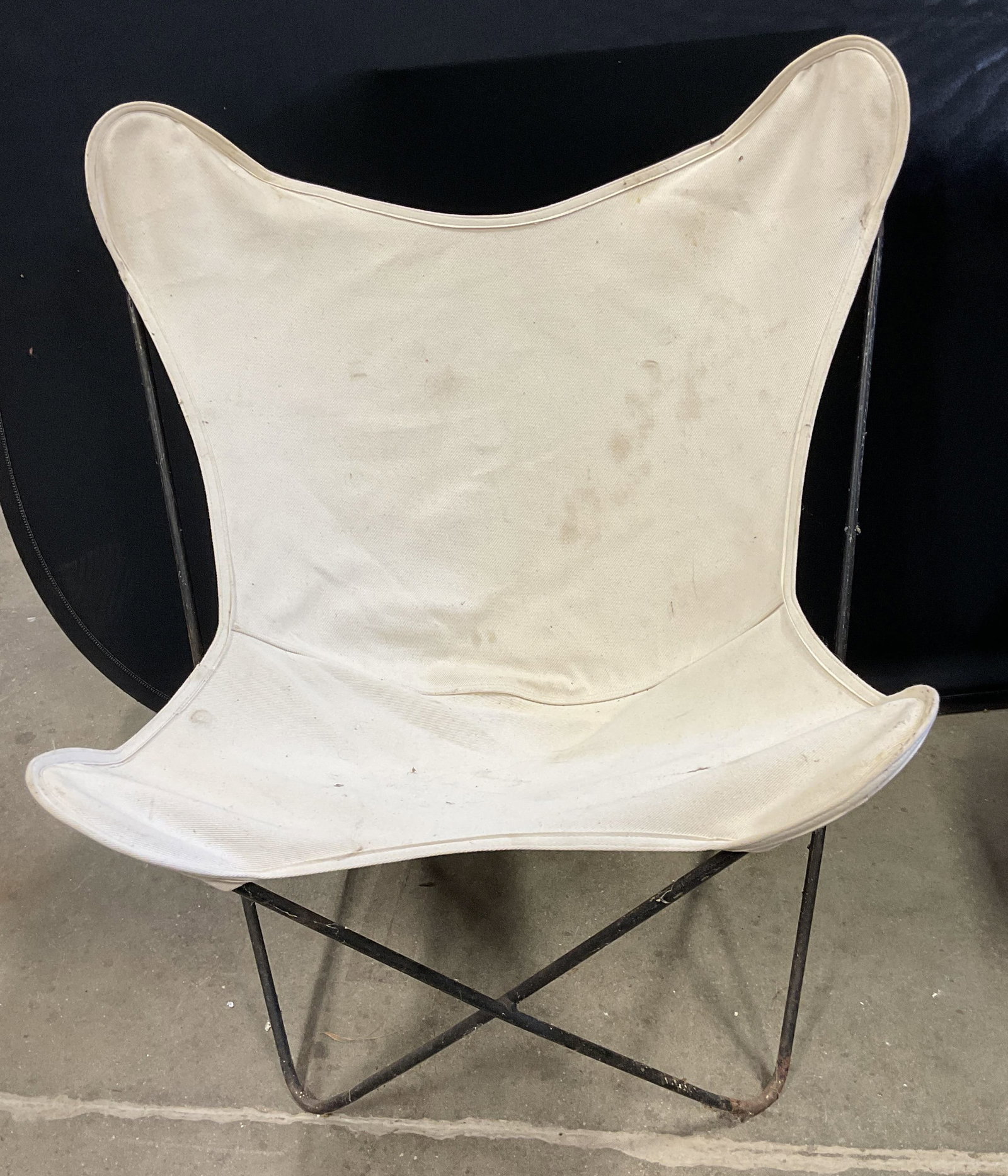 Black Frame White Canvas Butterfly Chair: Black metal frame butterfly chair with white canvas cover. Measures approx 33 x 29 x 24 inches. Patina, blemishes, and discoloration. Butterfly chair, metal, chair, canvas chair, white chair, furnitur
