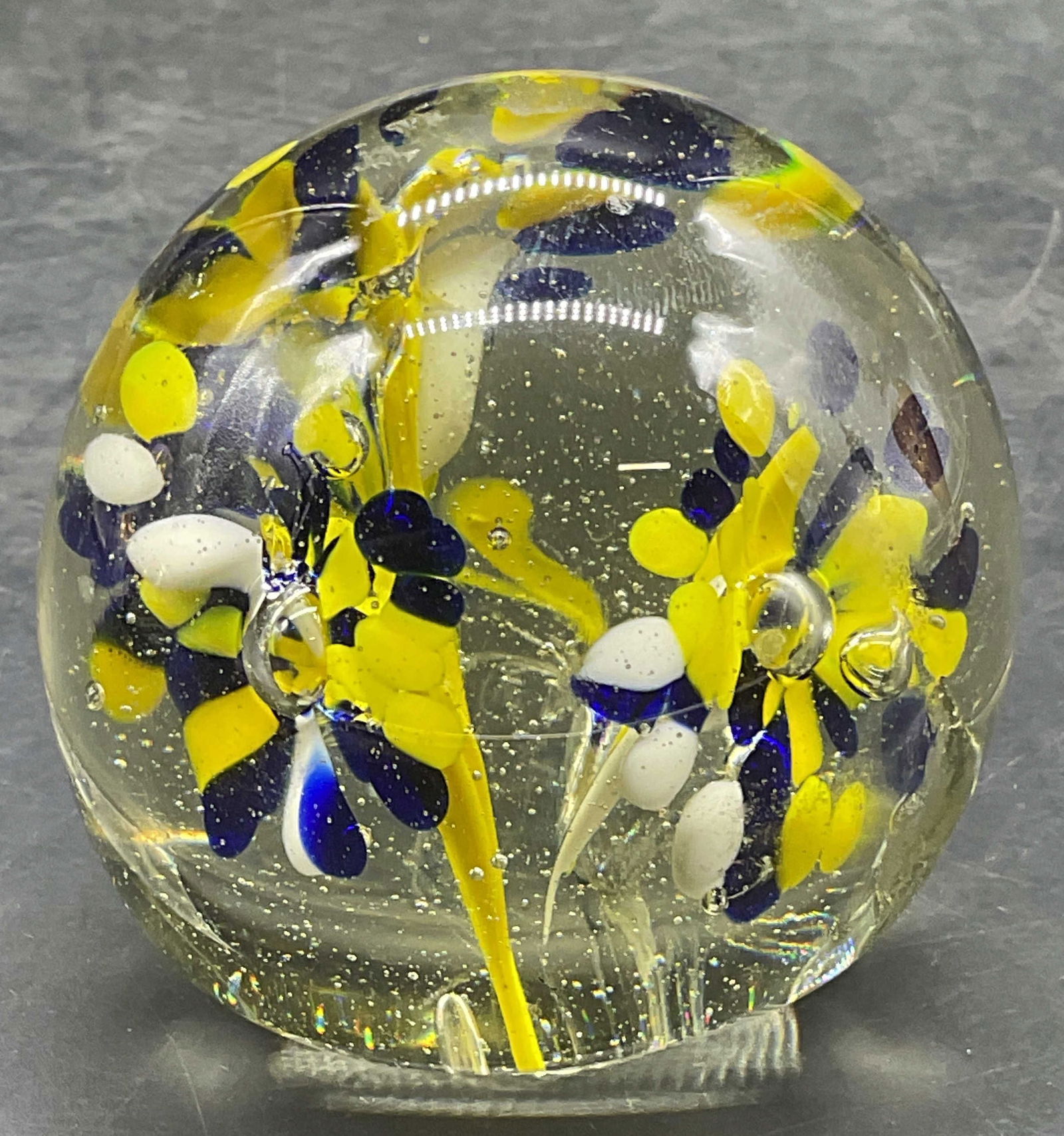Hand Blown Yellow Flower Art Glass Paperweight: Hand blown art glass paperweight. Blue, yellow and weight flower design. Piece has weight. Measures approx 2.5 inches wide. Some wear consistent with exposure. Art glass, art glass paperweight, decora