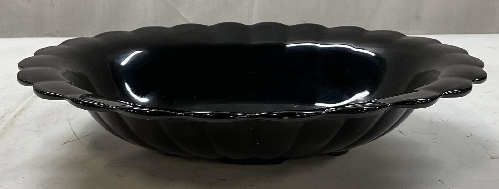 Vtg Scalloped Black Glass Decorative Bowl: Vintage scalloped black glass decorative bowl. Bowl with scalloped edges. Ribbed design and oval shaped base. Measures ht approx 3 inches diam approx 12 1/2 inches. Scratching observed and surface wea