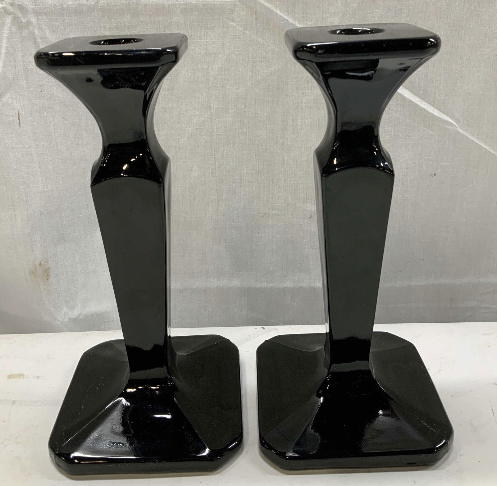 Vntg Pair Black Glass Faceted Candlesticks: Candlesticks are black glass & feature a faceted stem w square base. Glossy finish. Surface wear consistent to age, use & exposure. Measurements: length 4in x width 4in x height 8.4in. Black glass can