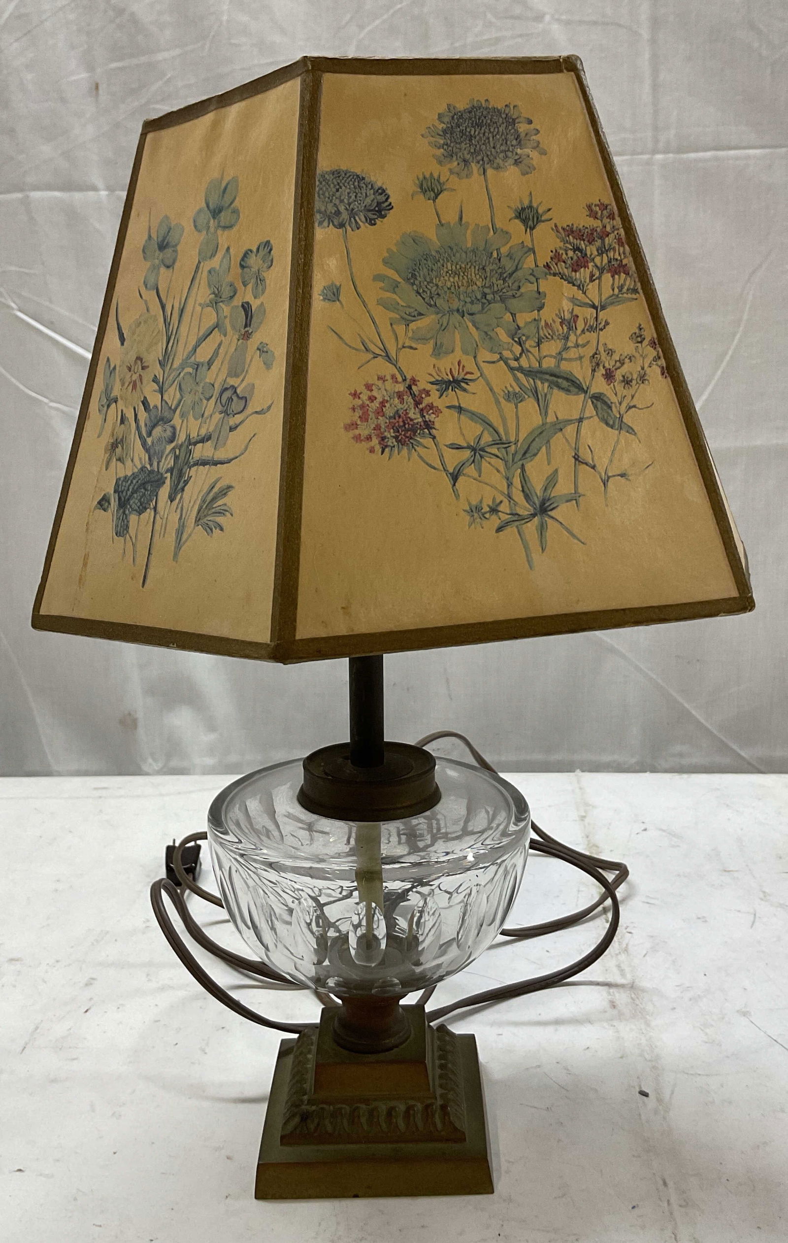 Vintage Lamp With Paneled Shade: Vintage lamp with paneled shade. Decorative brass square pedestal base. Shade features floral motifs in a vintage style. Colors include blue, red, and green. Decorative glass feature. Measures ht appr