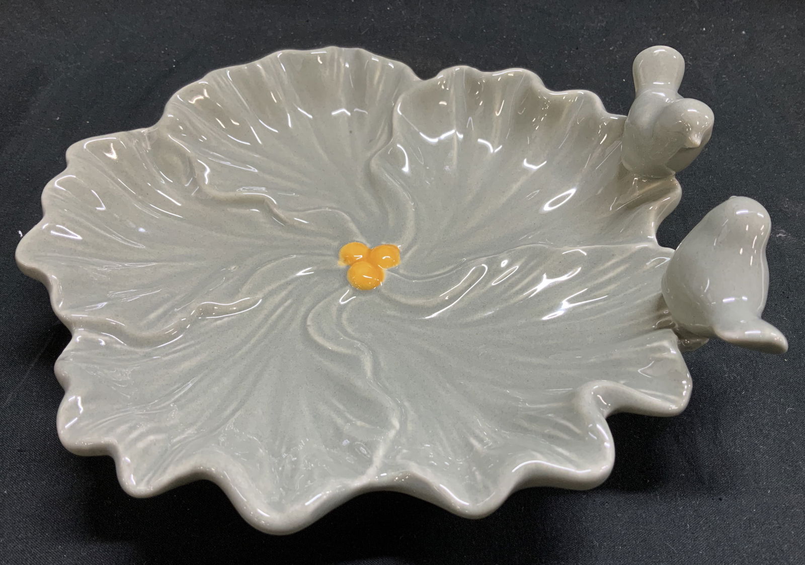 Green Glazed Perched Birds Leaf Shaped Dish: Ceramic leaf shaped dish featuring a scalloped edge & raised veining details. Center features yellow accents. 2 birds are perched on rim. Green glossy glazed finish. No visible signature or markings.