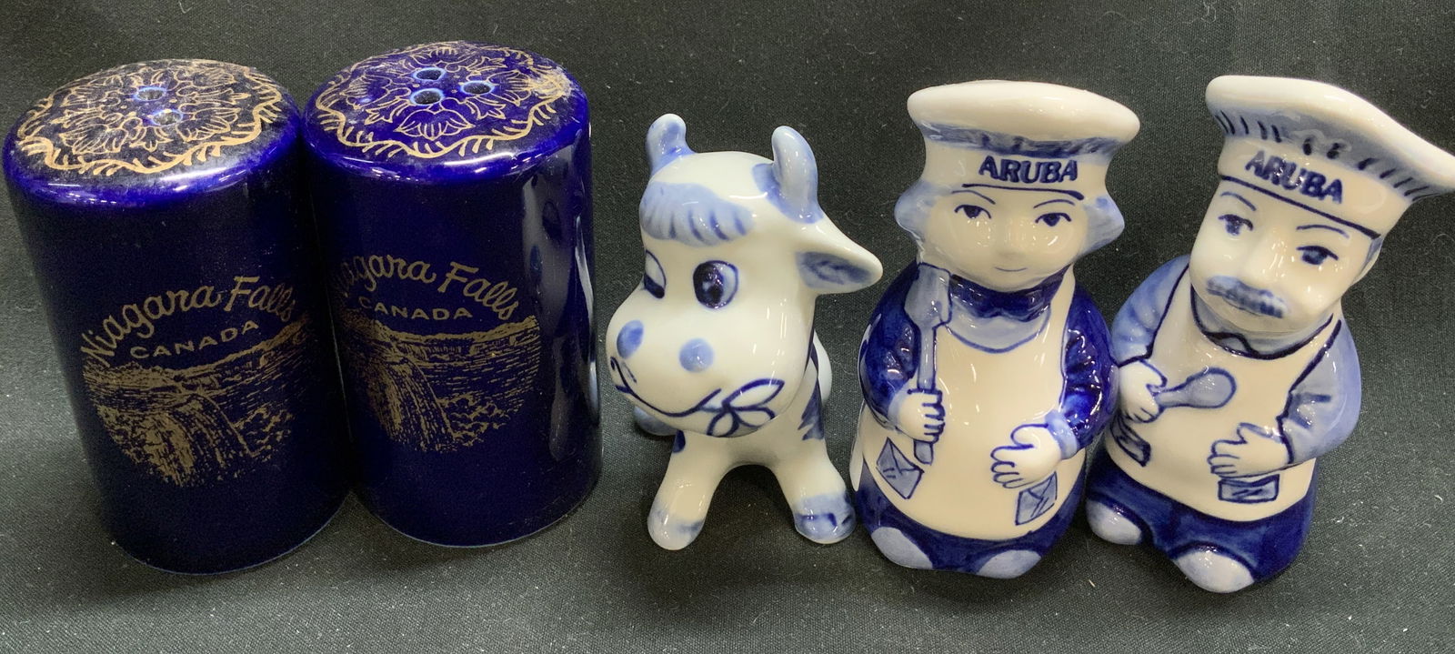 Set4 Ceramic Salt & Pepper Shakers & Cow Fig JAPAN: Lot includes, set 2 of ceramic salt & pepper shakers shaped like chefs w ARUBA written on their hats. Set 2 Niagara Falls Canada cobalt gilt salt & pepper shakers. 1 blue & white cow figurine. Signed