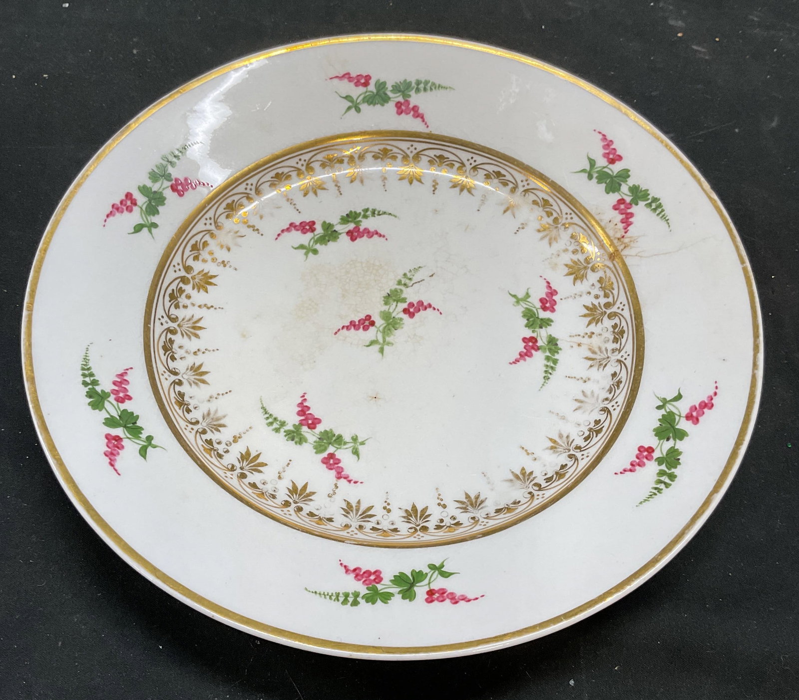Antique English Derby Hand Painted Porcelain Plate: Antique English porcelain plate. Signed on underside, appears to be a Derby mark. Hand painted grape design in pink and green with ornate girl border. Measures approx 8.75 inches wide. Wear including 