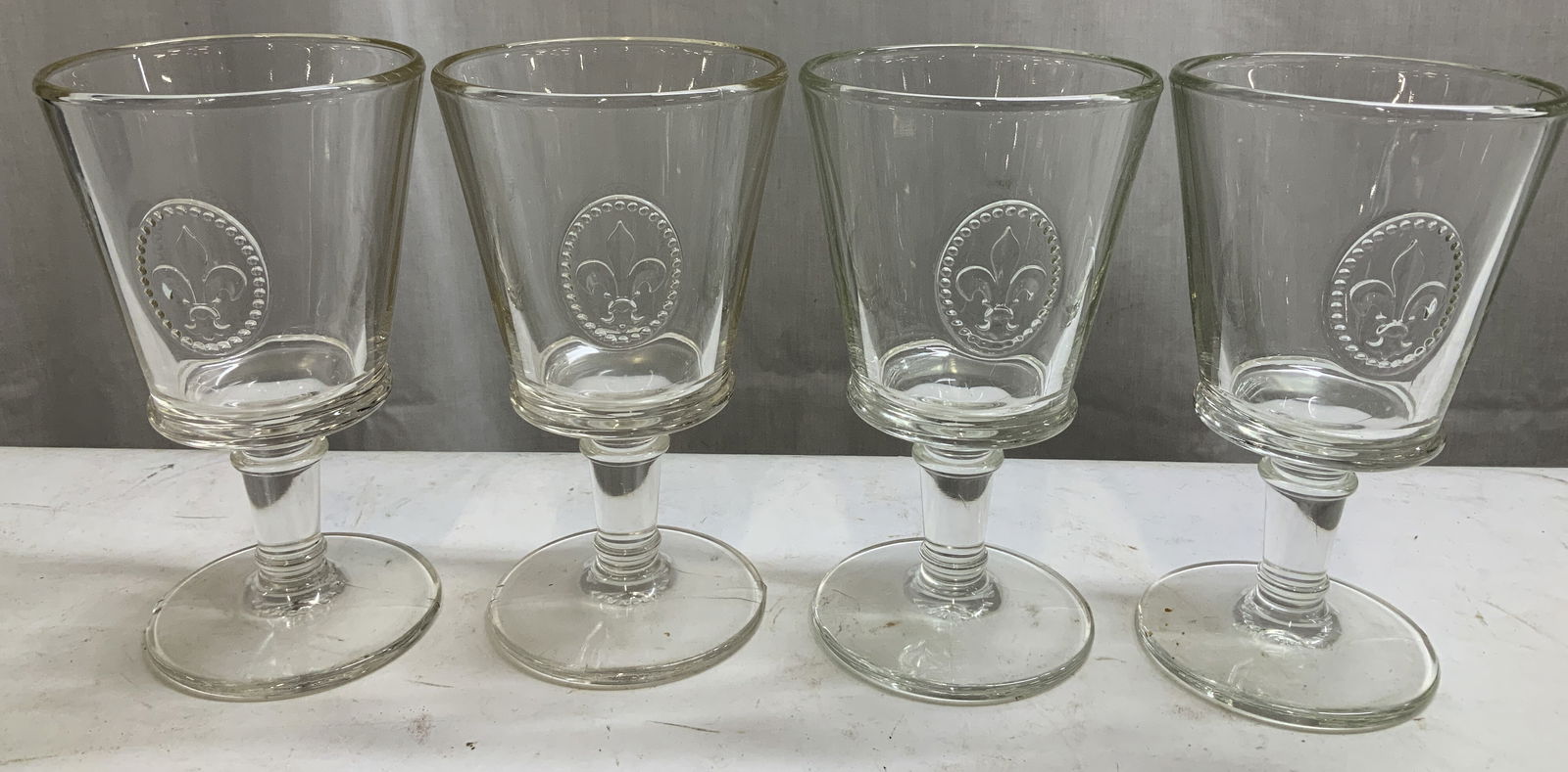 Set 4 La Rochere Fleur de Lys Wine Glasses FRANCE: Lot includes, set 4 of La Rochere clear wine glasses. Glasses feature an embossed oval medallion containing Fleur de Lys. Signed & marked on underside. Reads, LA ROCHERE FRANCE. Surface wear consisten