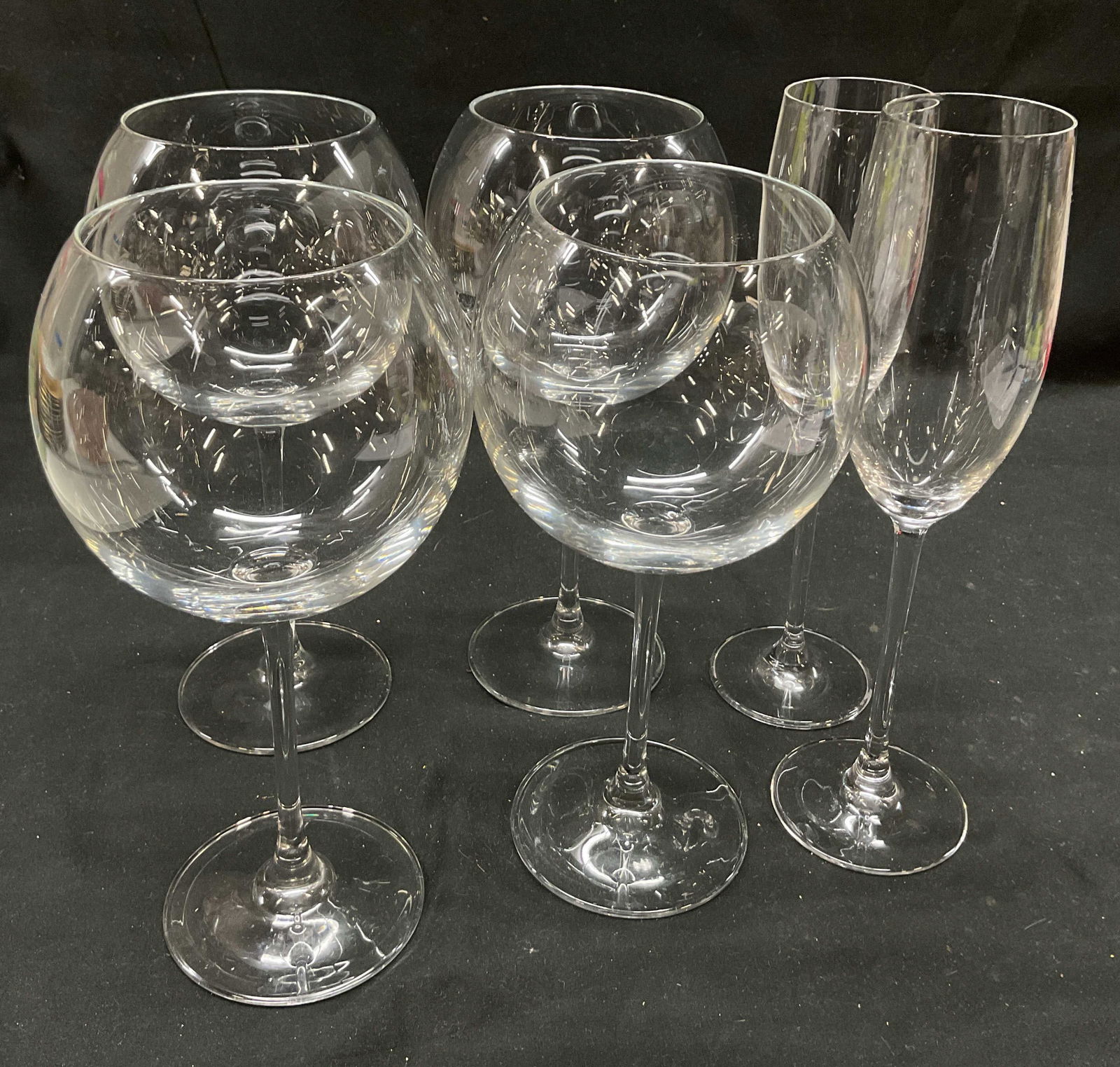 Lot 6 Wine Goblets & Champagne Flutes: Lot of 6 stemware glasses. Includes 4 wine goblet glasses and 2 champagne flute glasses. Narrow and wide rims. Largest piece measures ht approx 10 inches base diameter approx 3 inches. Surface wear co