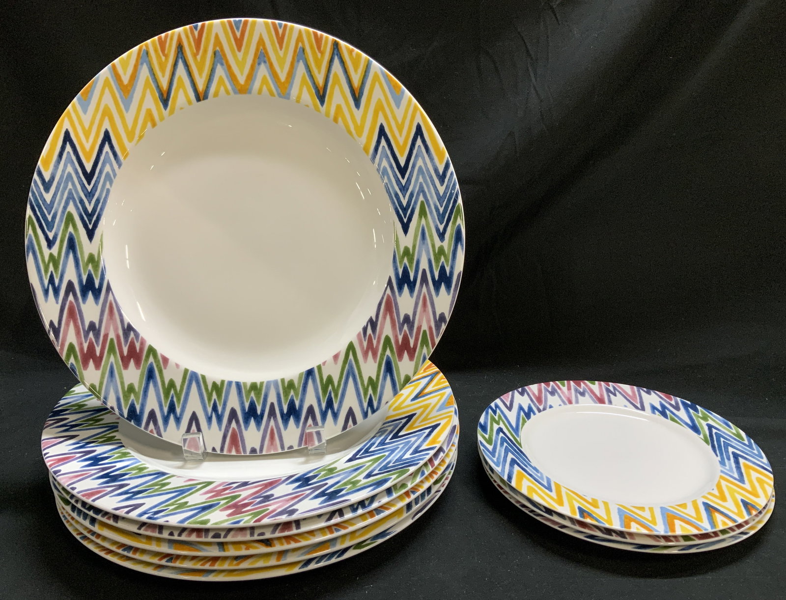 Set 9 Crate & Barrel Zigzag Chop & Salad Plates: Lot includes, 6 chop plates & 3 salad plates. Pieces features a colorful, bold zigzag design around the rim in shades of yellow, blue, green, and pink. Signed & marked on underside. Reads, CRATE & BAR