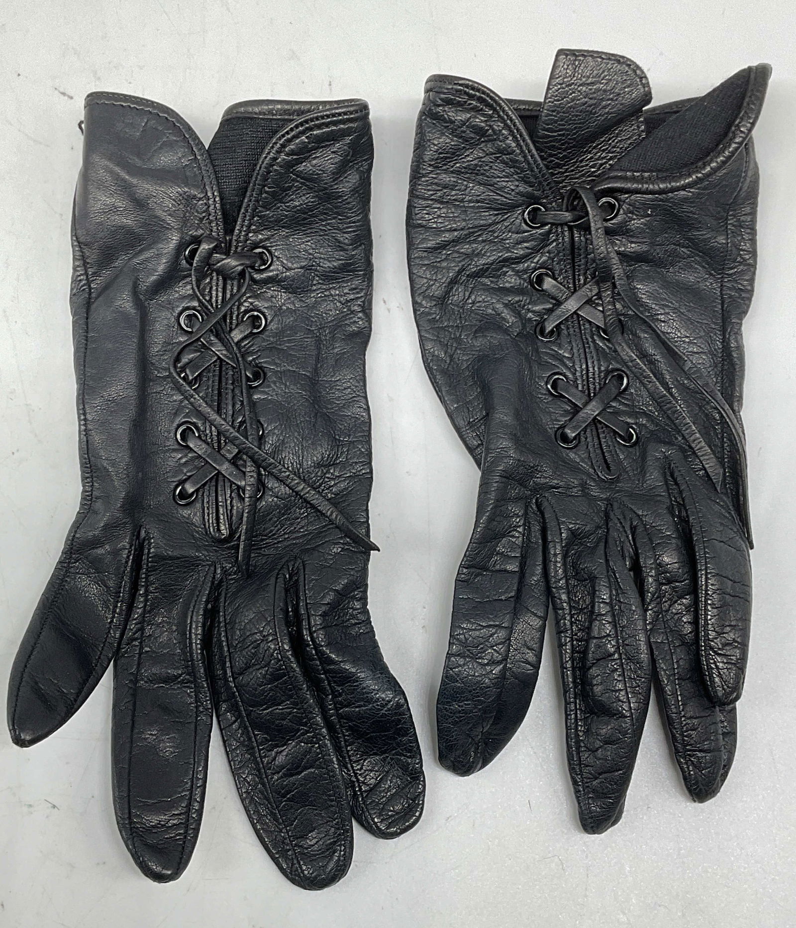Black Leather Lace Up Silk Lined Gloves: Black leather lace up gloves with silk lining. Measure approx 3 inches wide, 7.25 inches long. Some wear to leather consistent with exposure. Leather gloves, silk lined gloves, black gloves, lace up g
