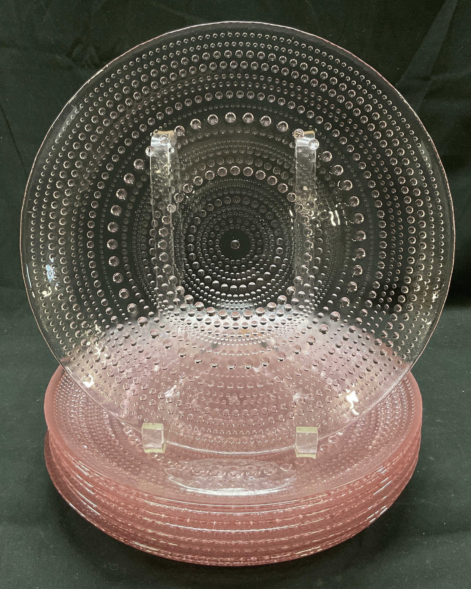 Set 9 Pink Toned Hobnail Glass Plates: Set of 9 pink toned glass plates. Hobnail / Raised dotted pattern. Measures approx 10 1/2 inches wide. Some scratching observed and surface wear consistent with exposure. Plates, glass plates, tablewa