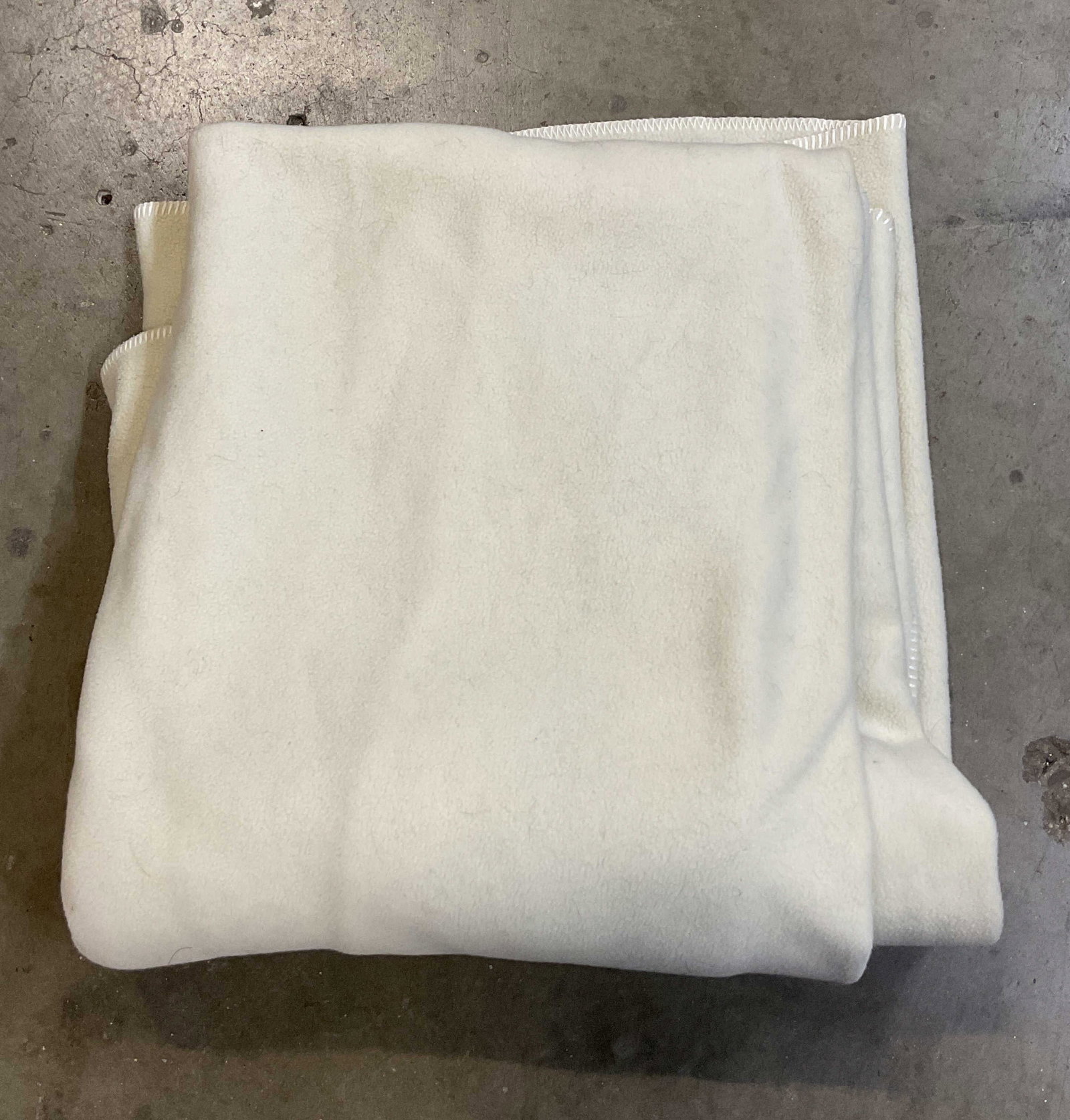 Polartec The Snuggable Cream Blanket USA 50in: Polartec The Snuggable cream colored blanket. Made in USA. Polyester material. White stitched trim. Unique stitching throughout blanket. Measures approx 46 x 50 inches. Wear consistent with exposure.
