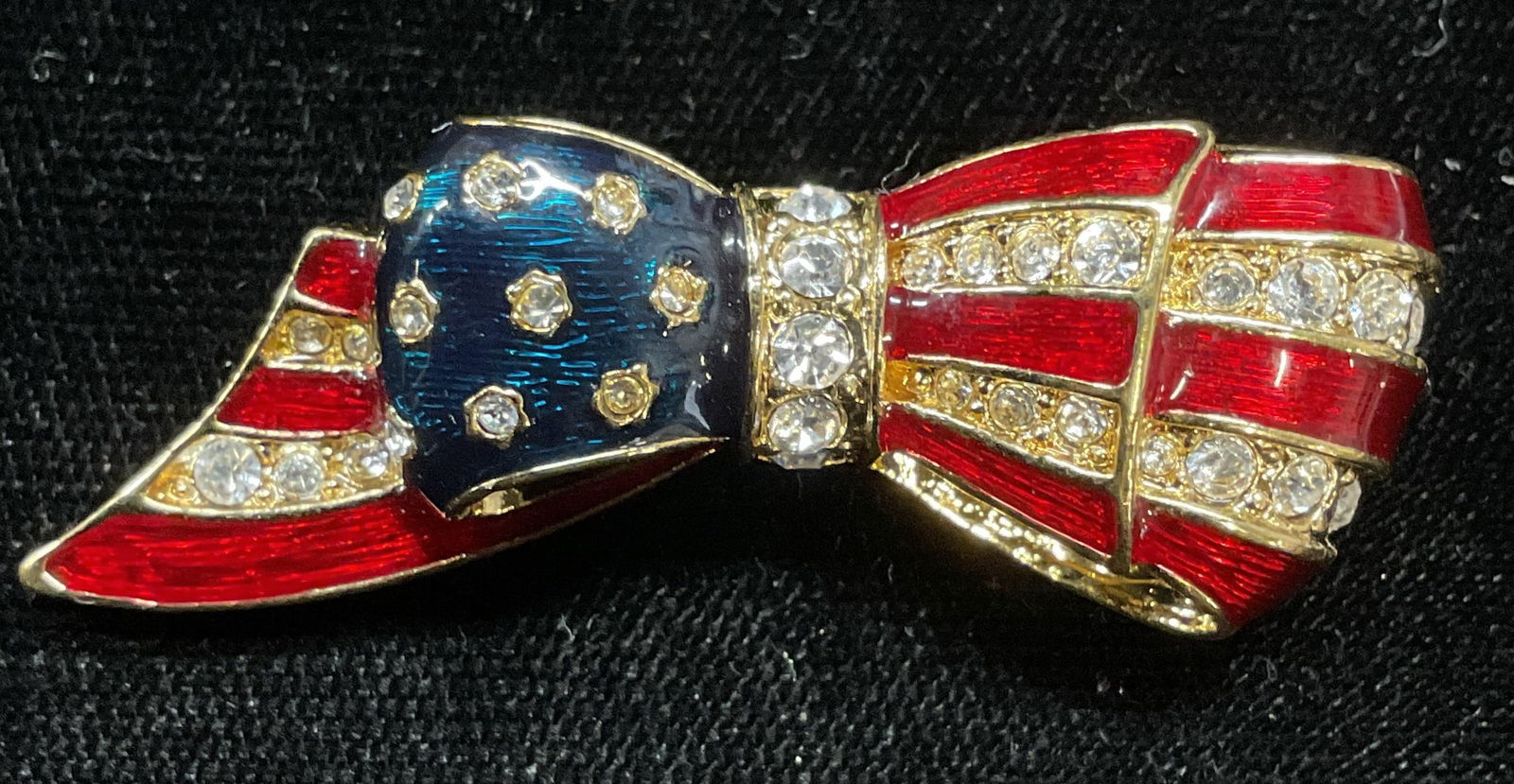 Carolee Gold Tn Enamel USA Flag Brooch: Signed Carolee gold tone enameled American flag bow brooch with colorless crystals. Measures approx 1.75 x .75 inches. Some scratching. Jewelry, estate jewelry, costume jewelry, cocktail jewelry, fash