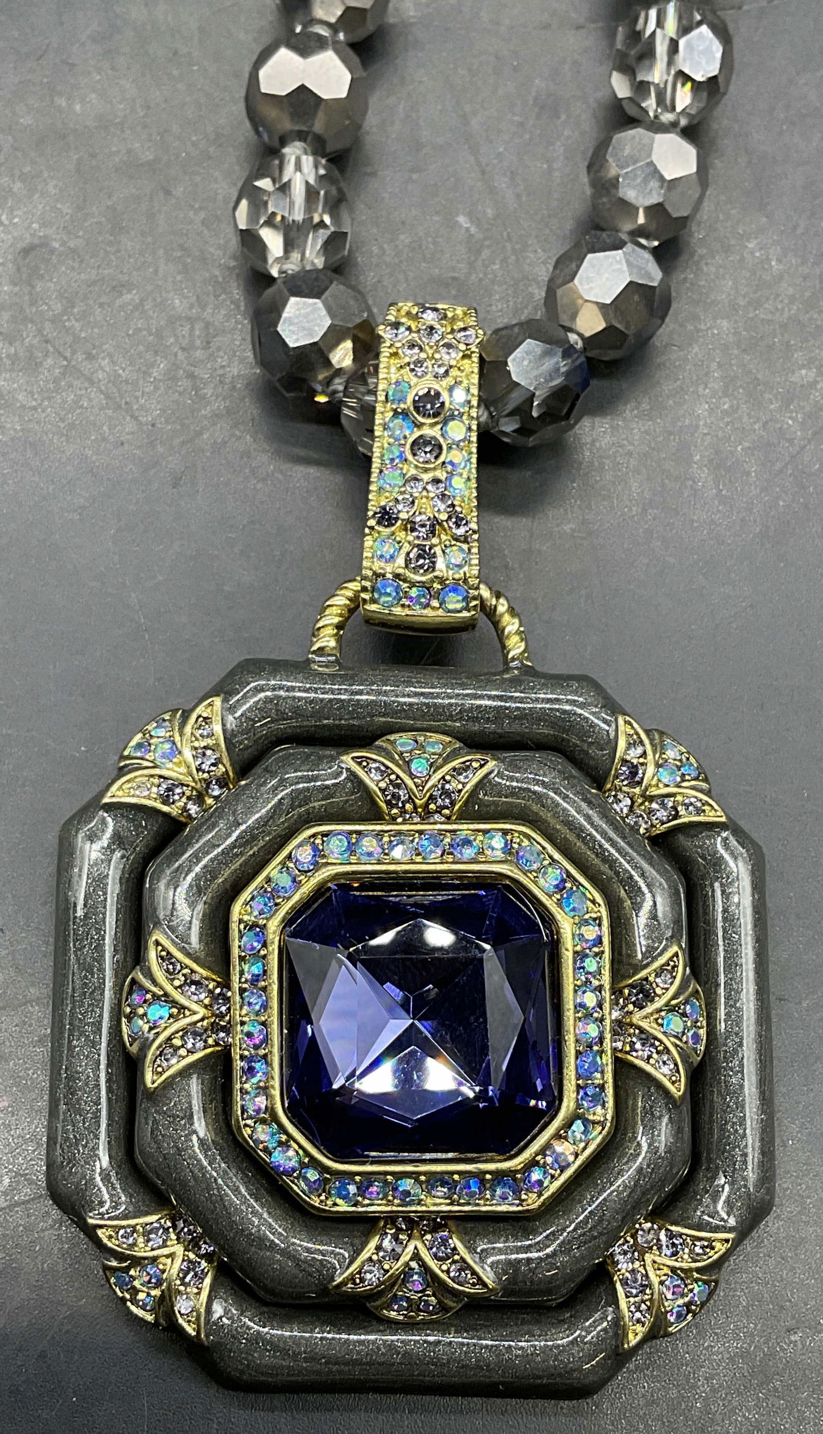 Heidi Daus Grey Crystal Enamel Pendant Necklace: Signed Heidi Daus gold and grey enameled pendant necklace with blue crystal decoration and grey crystal beads. Drop length approx 10 inches. Pendant approx 3 x 2 inches. Some scratching. Jewelry, esta
