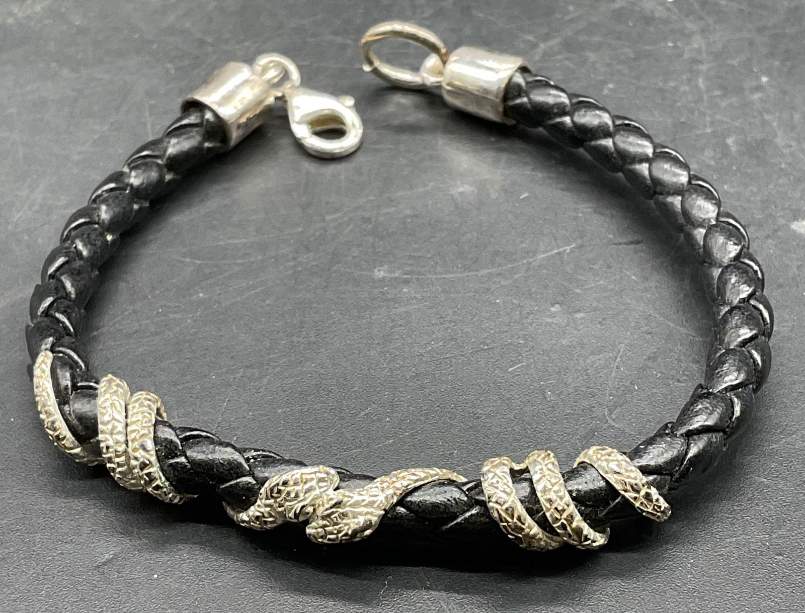 Sterling Silver Black Leather Snake Bracelet: Braided black leather and sterling silver snake motif bracelet. Measures approx 6.5 inches long. Some scratching. Jewelry, estate jewelry, fine jewelry, cocktail jewelry, fashion jewelry, accessories,