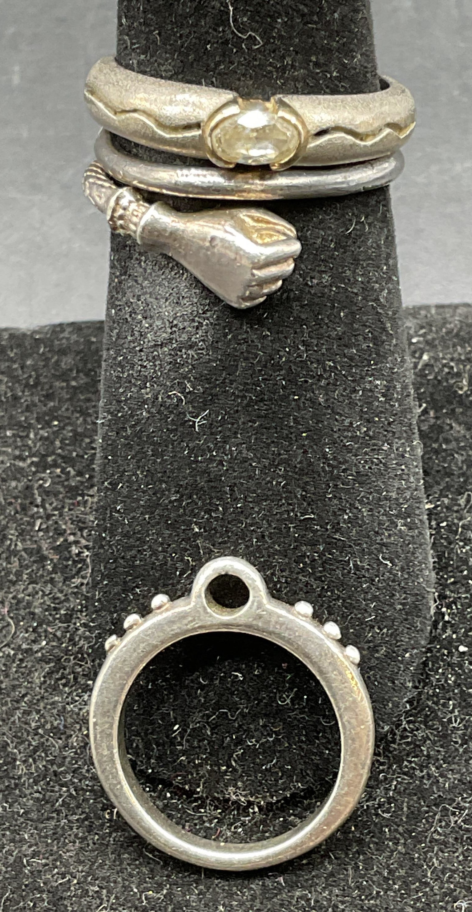 Lot 3 Sterling Silver Rings & Pendant: Lot of 3 sterling silver rings and pendant. Adjustable band hand motif ring, ring with semiprecious stones, open circle pendant. Semiprecious ring size 5.5. Total weight of all pieces 7.4 grams. Marke