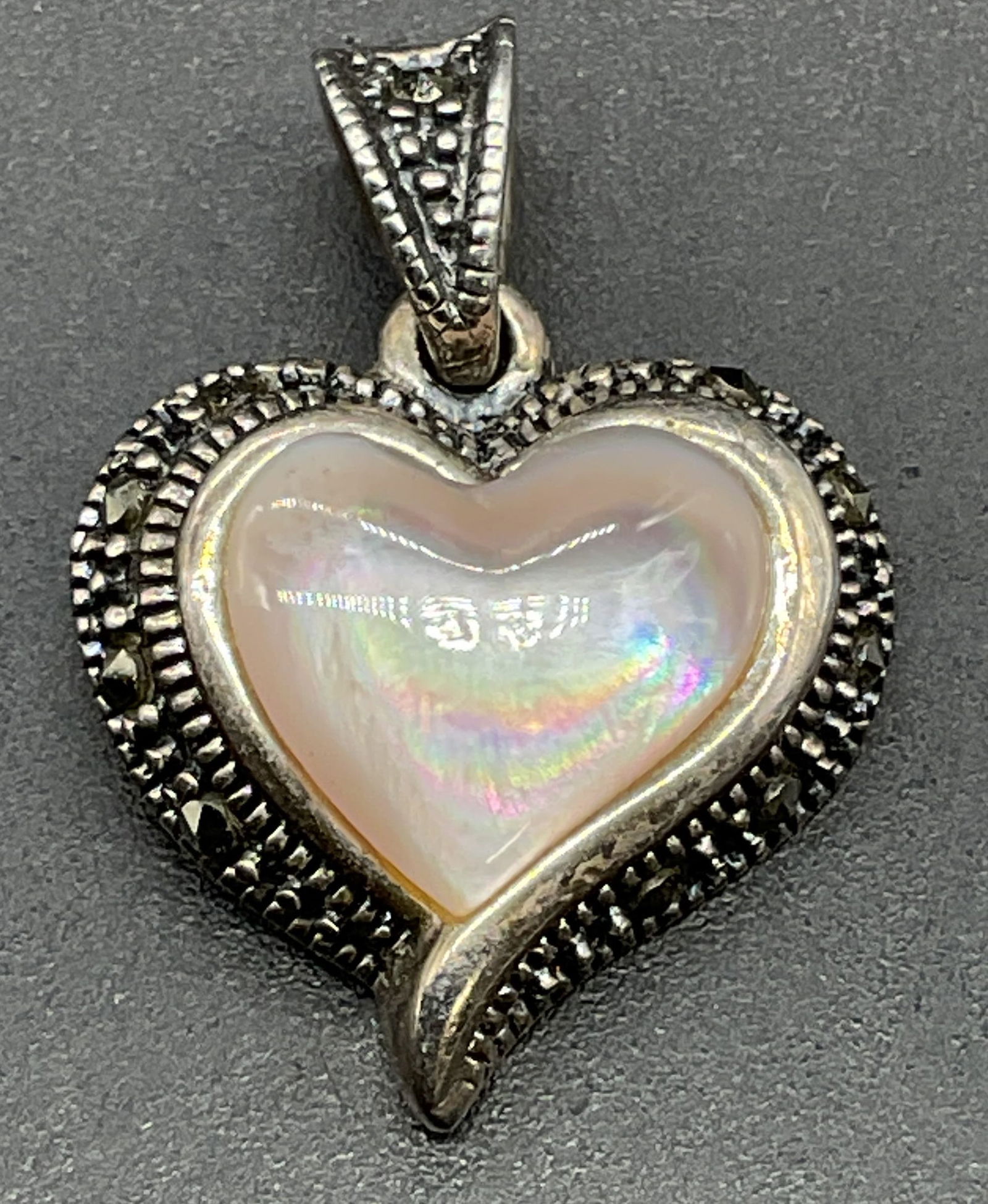 SLC Sterling Silver Mother of Pearl Heart Pendant: Signed SLC sterling silver pink mother of pearl and marcasite heart pendant. Measures approx .5 x 5/8 inches. Total weight 3.1 grams. Some scratching. Jewelry, estate jewelry, fine jewelry, cocktail j