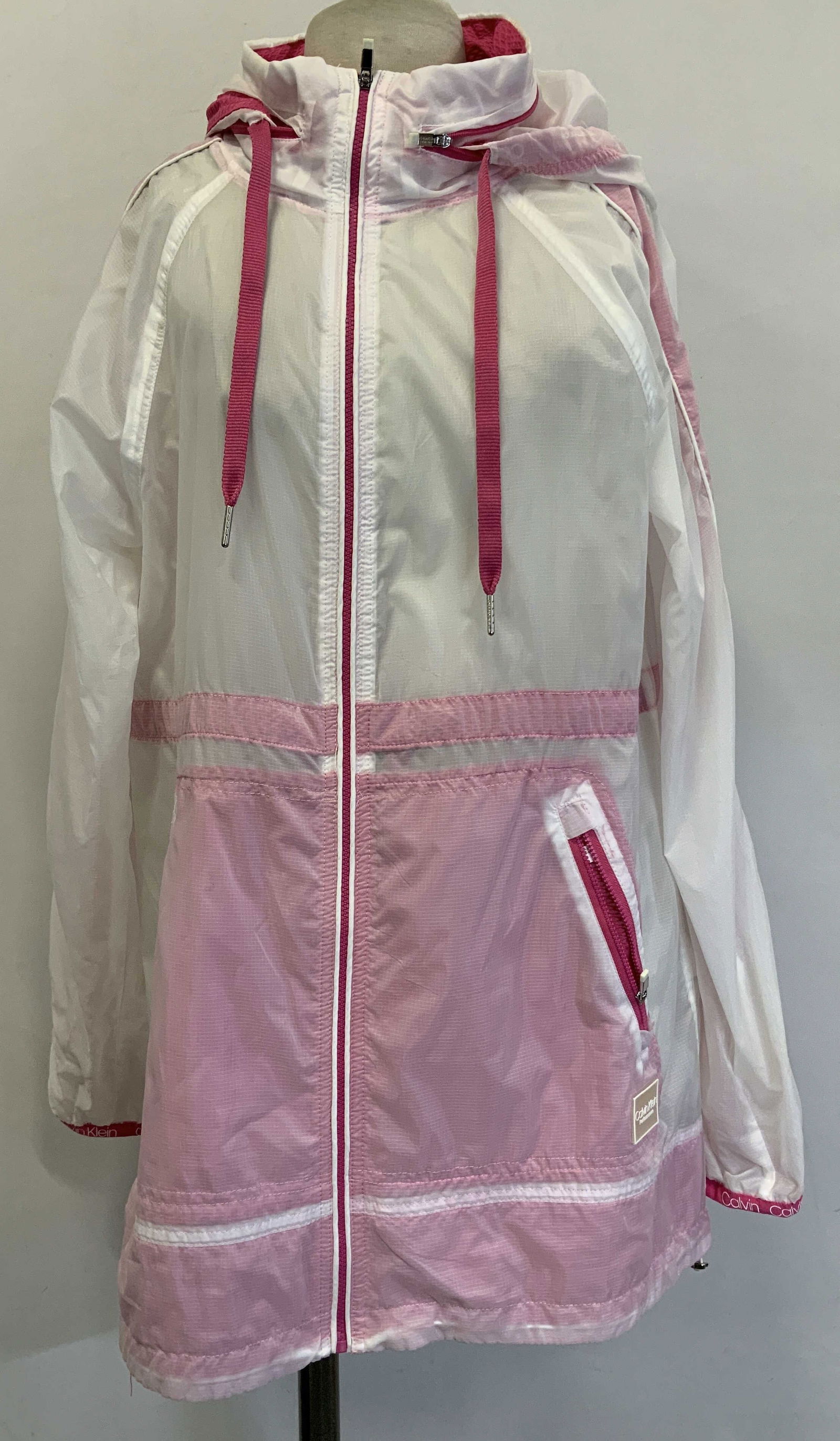 Calvin Klein Performance Pink & White Jacket: Calvin Klein performance jacket is 100% polyester. Size medium. Jacket is pink & white. Transparent style. Zippered pockets. Signed & marked. Reads, CALVIN KLEIN PERFORMANCE. Surface wear consistent t