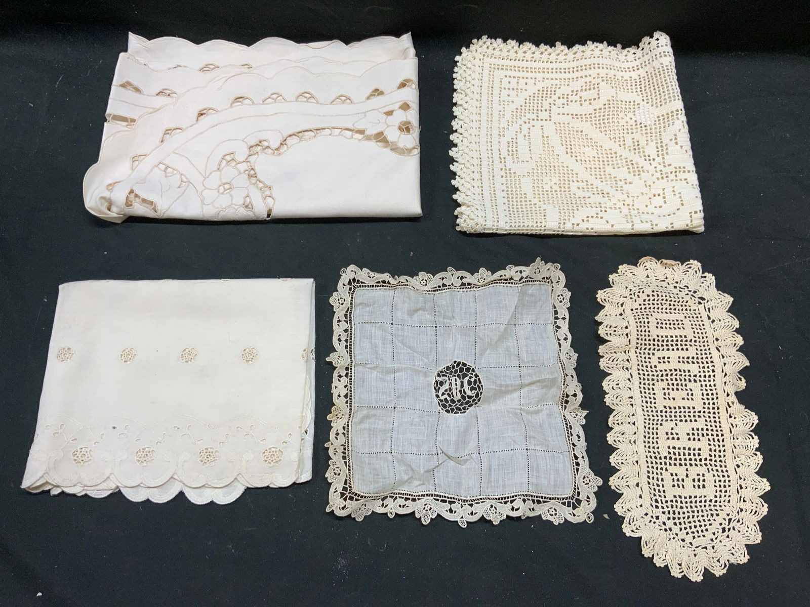 Lot 5 Vtg Assorted Lace Table Linens & More: Lot includes 2 table runners with floral and leaf patterned edges, 1 lace decor piece which reads BREAD, 1 Handkerchief, & 1 square. Table runner measures approximately 46 inches long 14 inches wide.