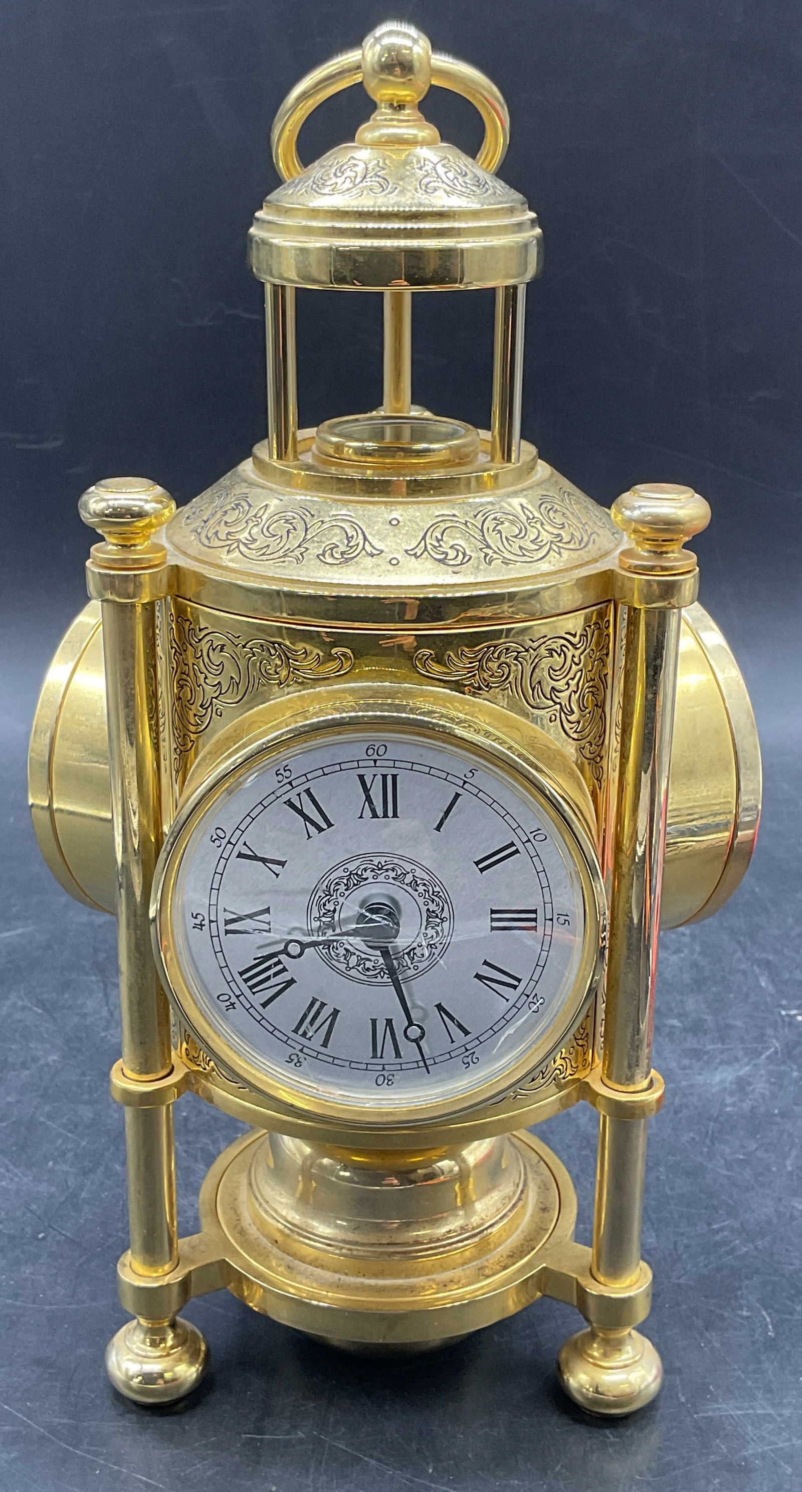 Franklin Mint Gold Plated Meteorological Clock: Franklin Mint meteorological clock. Weather station. Includes a clock, barometer, thermometer, and compass on 4 faces. Gold plated metal. Ornate scroll decoration. Footed base with top handle. Battery