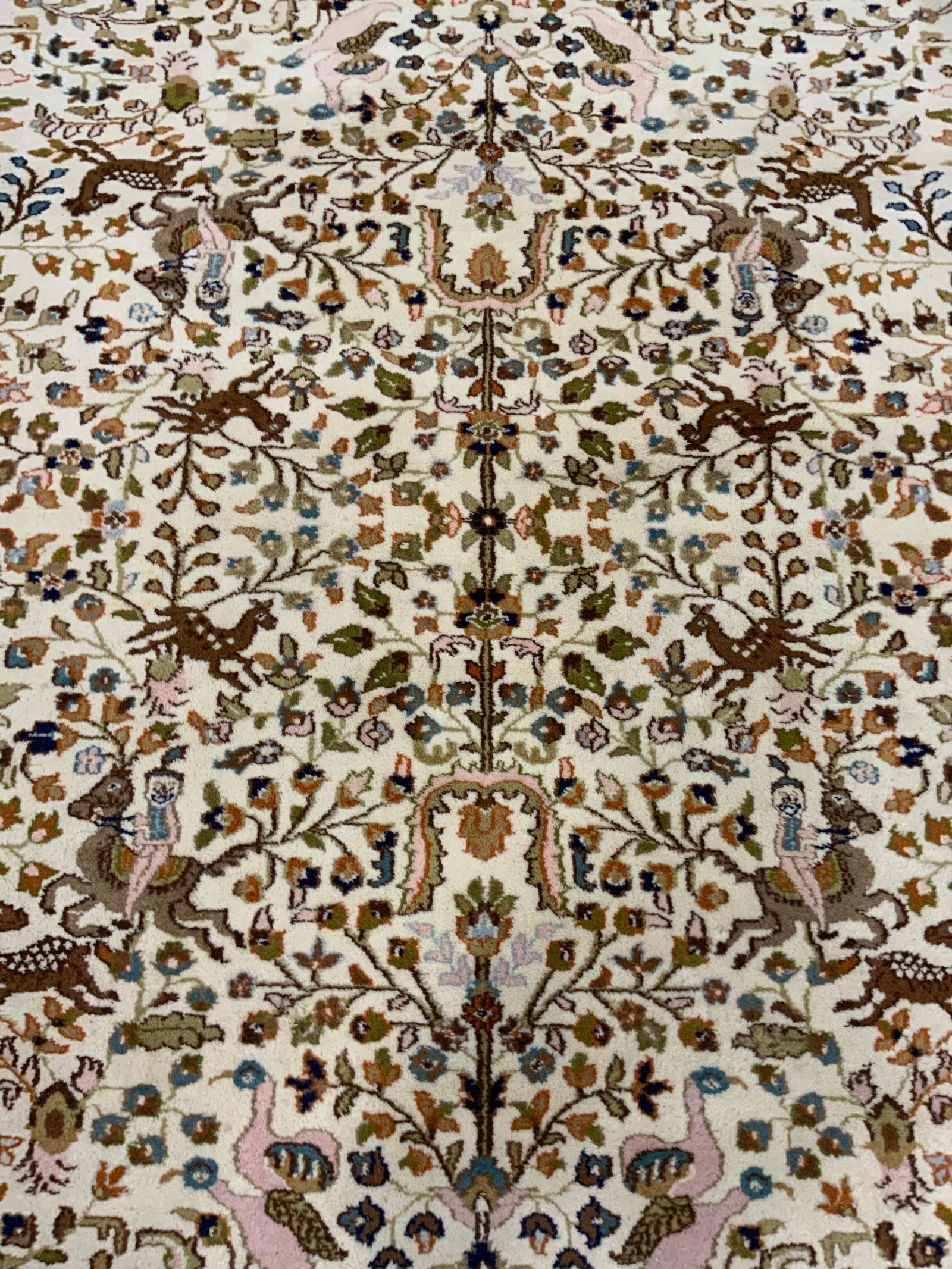 Handmade Room Size Fringed Wool Area Rug: Rug appears to be handmade and wool. Oriental style rug with intricate multi toned floral motif detail. Rug has cream base toned. Additional detailing includes deer and birds. Edges of rug have cream