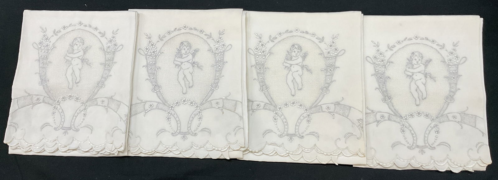Set 4 White Embroidered Cherub Linen Tea Towels: Set of 4 white embroidered cherub linen tea towels. Linen material. Features embroidered cherub motif surrounded by floral motifs. Embroidered ornate scroll designs. Scalloped trim. Measures approx 21