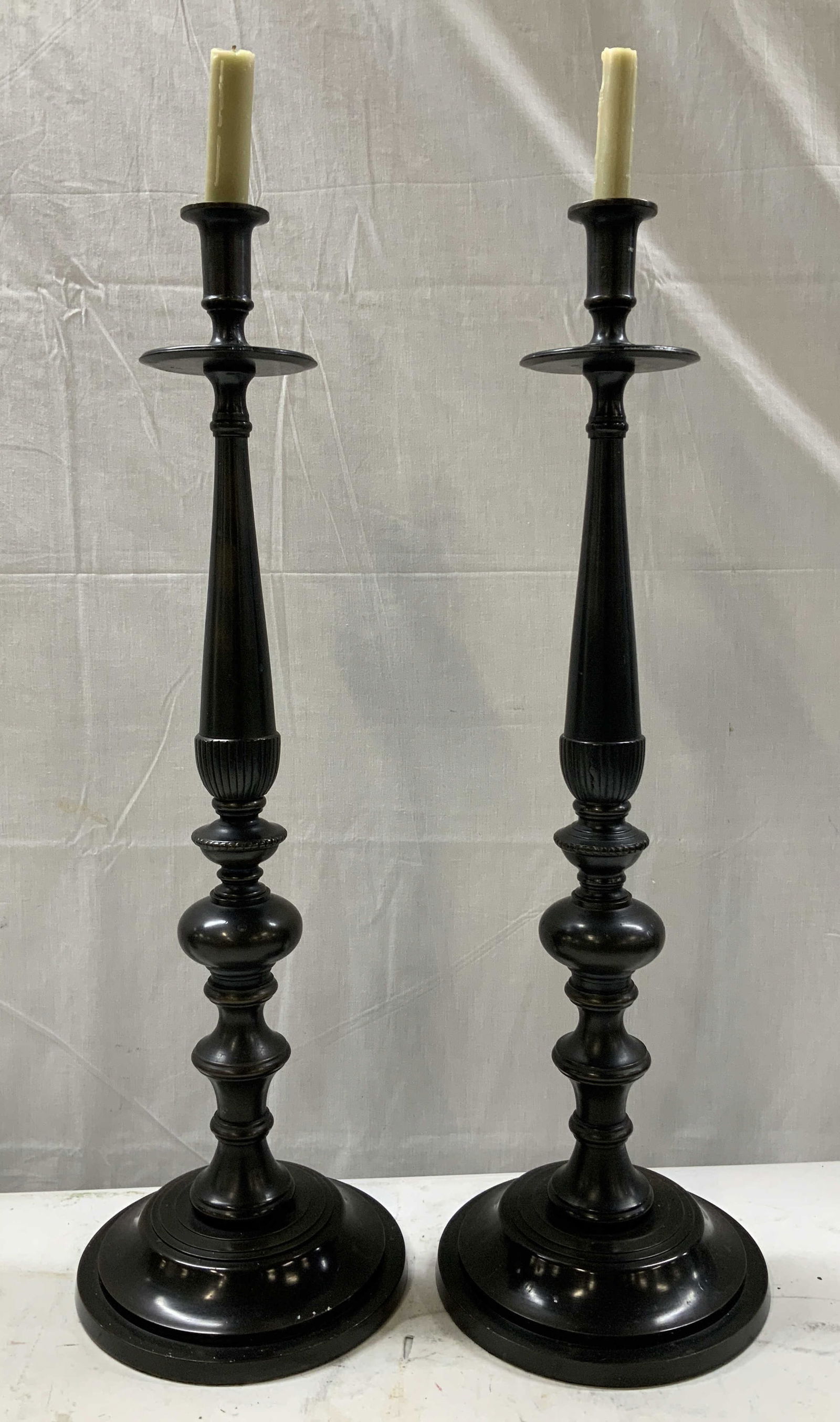 Pair Bloomingdales Bronze Patina Candleholders 26i: Lot includes, pair of Bloomingdales bronze patina metal candleholders. Pieces have weight. Each candleholder has a circular drip pan & baluster form stem. Stepped round base. Signed & marked on unders
