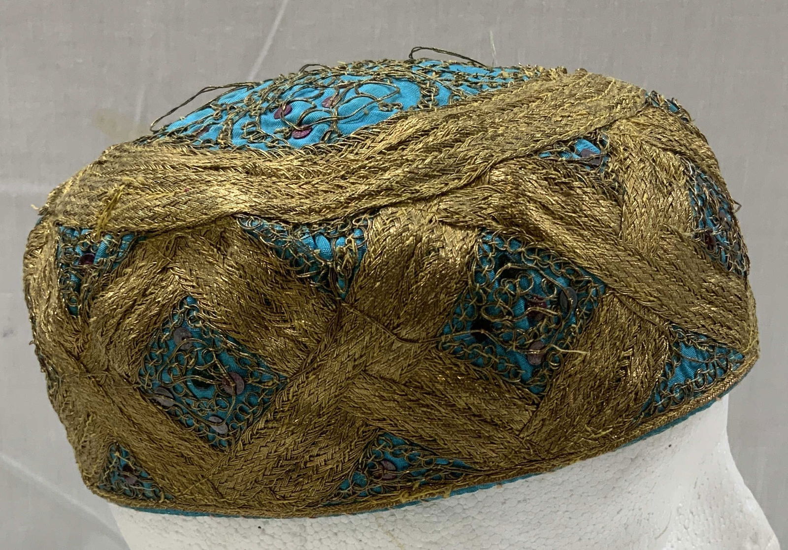 Vtg Hand Embroidered Turquoise & Gold Kufi Cap: Vintage kufi cap features gold thread x pattern embroidery throughout cap & a turquoise base. Embellished with small green & pink sequins. Surface wear consistent to age, use & exposure. Measurements: