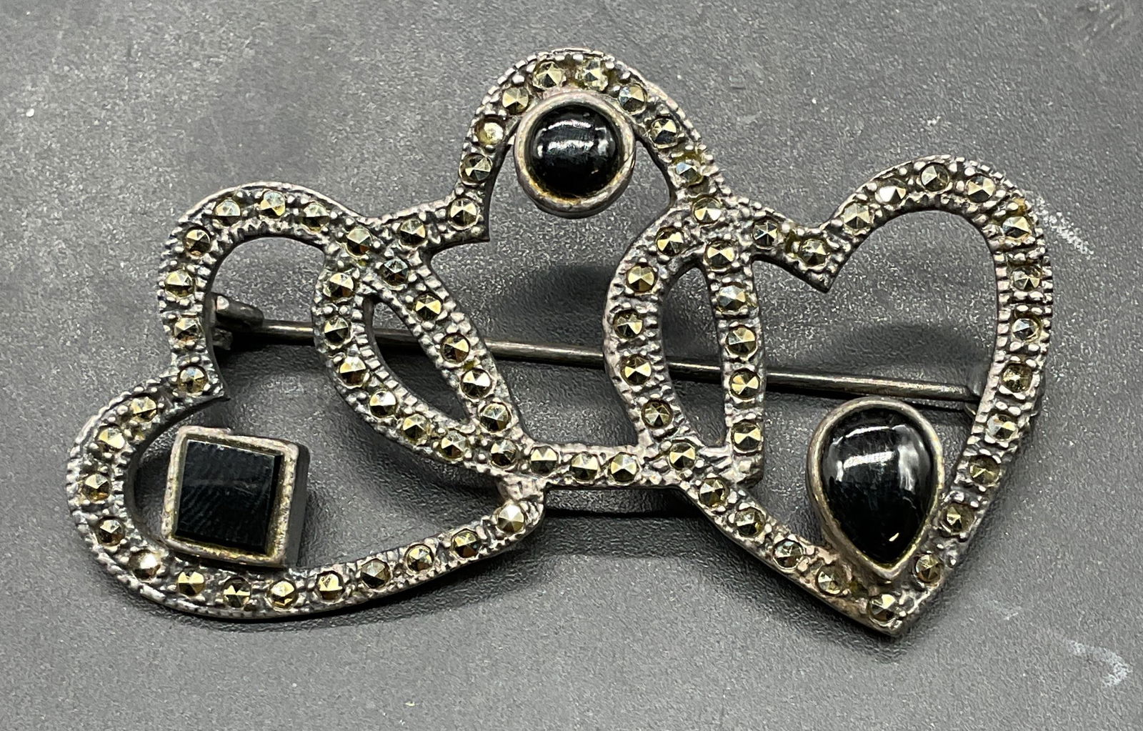 Sterling Silver Onyx Marcasite Heart Brooch: Sterling silver triple heart brooch with black onyx and marcasite. Measures approx 2 x 1.25 inches. Total weight 8.8 grams. Marked sterling. Some scratching. Jewelry, estate jewelry, fine jewelry, coc