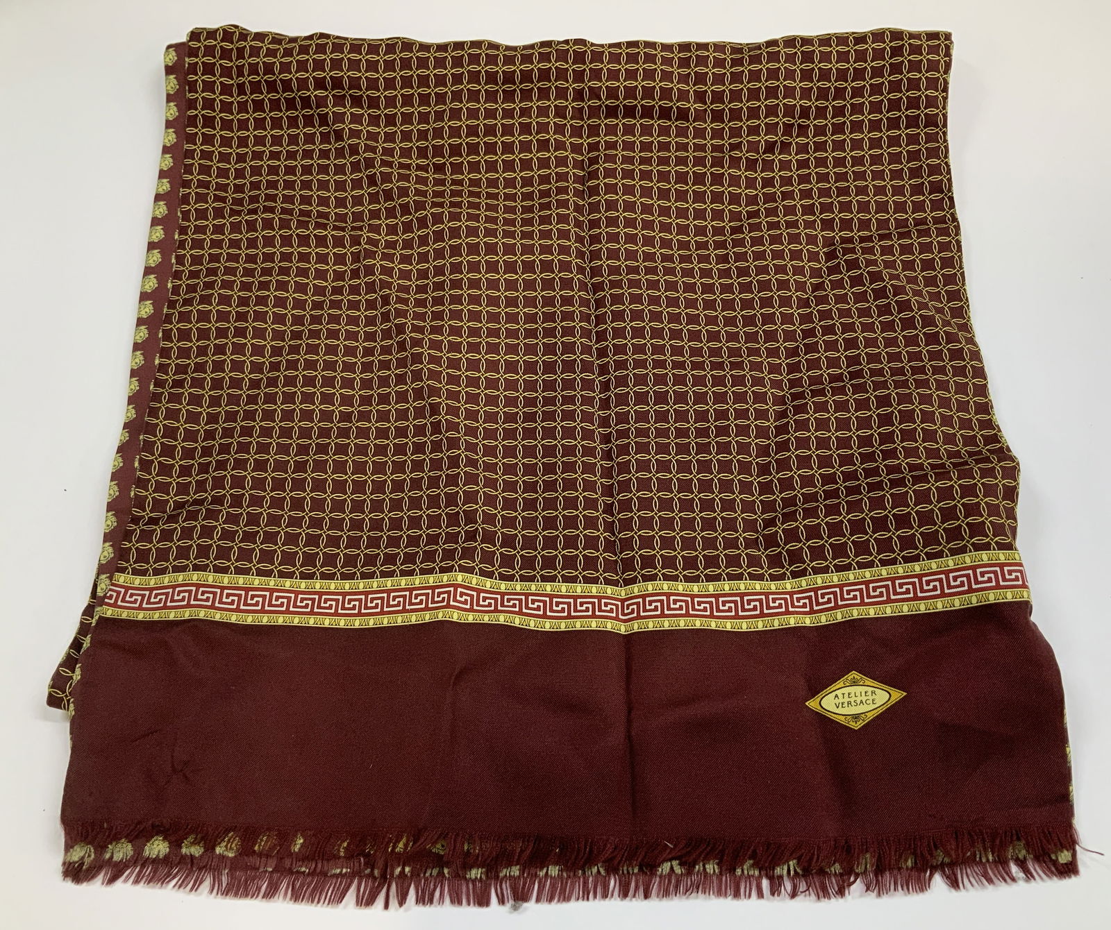 Vtg Atelier Versace Maroon & Gold Silk Scarf: Scarf is 100% silk. Features a repeating geometric pattern of gold interlocking circles. Underside of scarf has Medusa style head motifs. Fringed ends. Property of Upper East Side French stage & scree