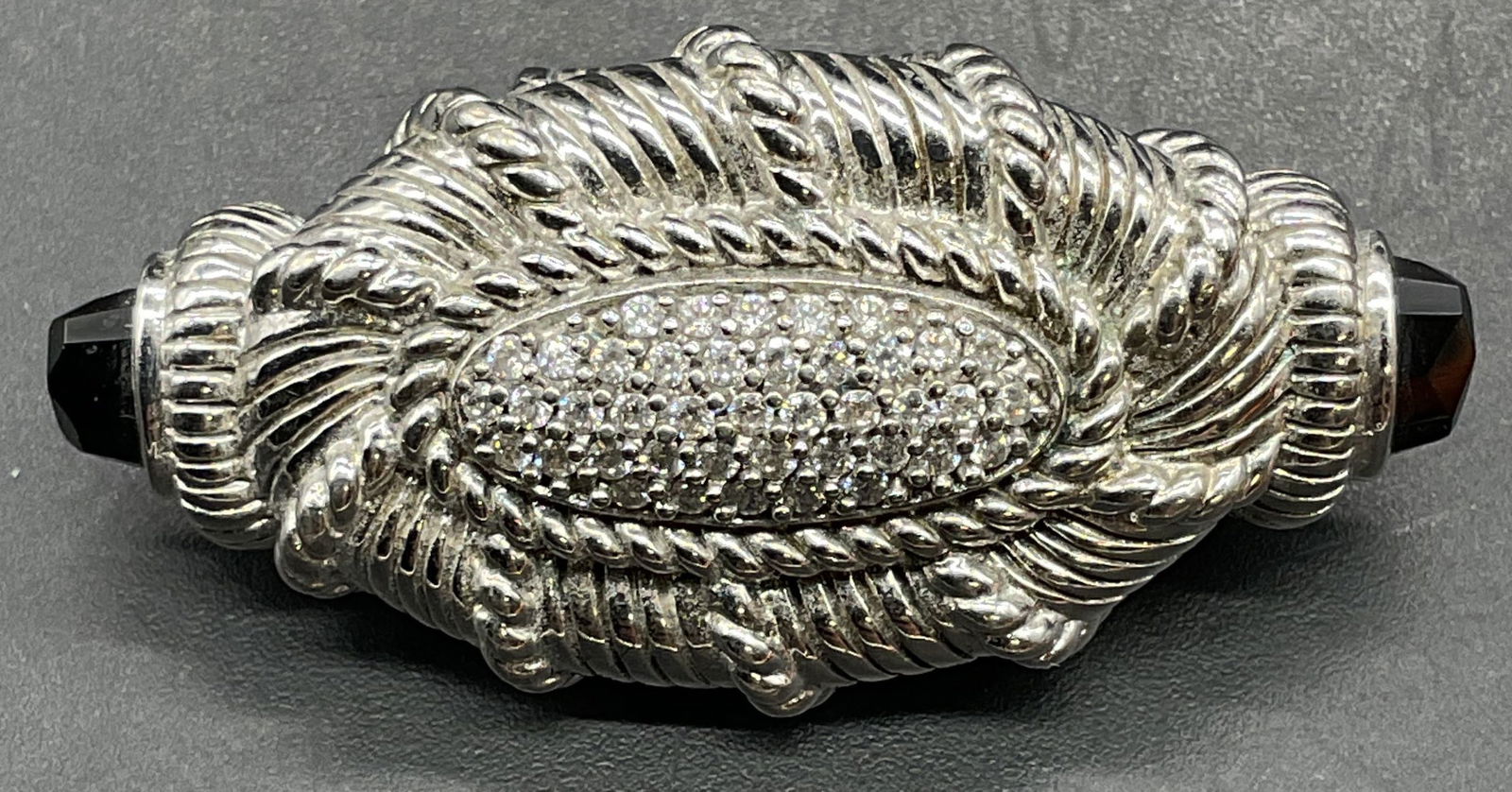 Judith Ripka Sterling Silver Onyx Brooch Pendant: Signed Judith Ripka sterling silver brooch pendant with cubic zirconia and black onyx gemstones. Measures approx 1.5 x .75 inches. Total weight 13.6 grams. Marked sterling. Some scratching. Jewelry, e