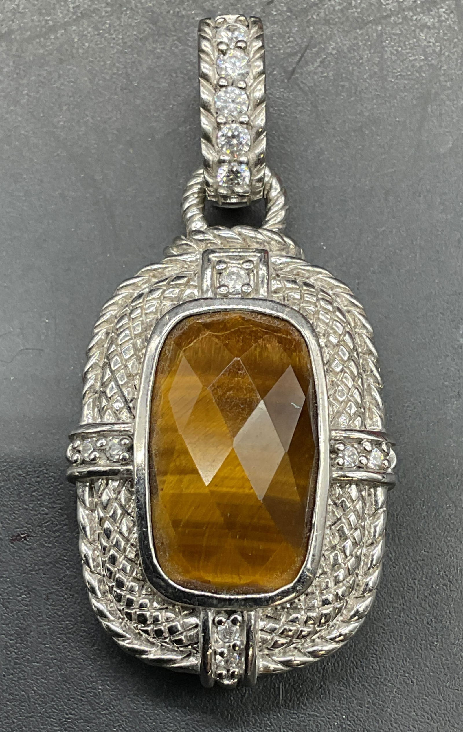 Judith Ripka Sterling Silver Tigers Eye Pendant: Signed Judith Ripka sterling silver pendant with tigers eye faceted gemstone and cubic zirconia accents. Measures approx 1.75 x .75 inches. Total weight 10.3 grams. Marked sterling. Some scratching. J