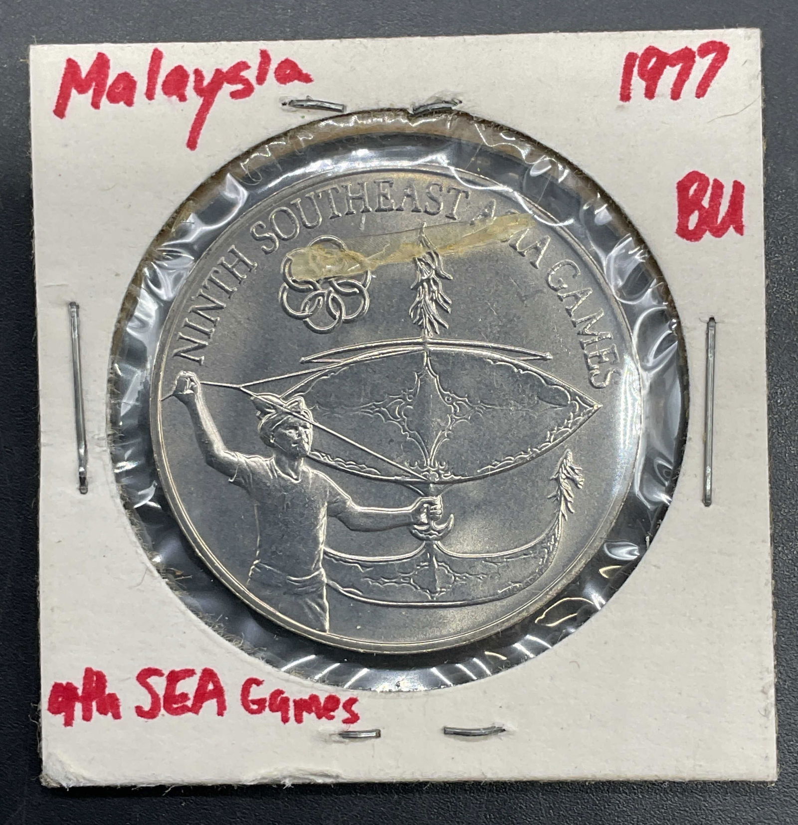 1977 Malaysia 1 Ringitt Commemorative Coin: 1977 Malaysia 1 Ringitt coin commemorating the 9th Southeast Asian Games. Reverse features man flying traditional Malaysian kite, obverse features Malaysian Cot of Arms. Copper nickel alloy. Held in p