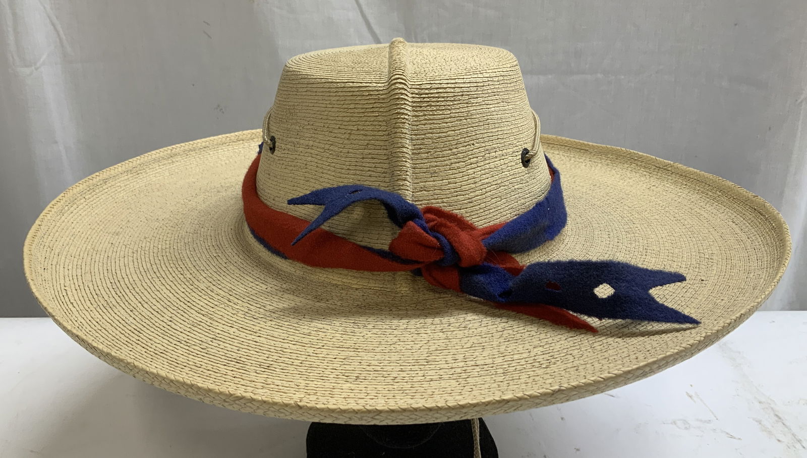 J.B. Handwoven Straw Hat W Red & Blue Band: Handwoven straw hat with a red & blue fabric band tied into a bow. Attached with an adjustable chin chord. Signed & marked on underside. Hand written inscriptions that reads, PAUL ADDAMS. J.B. Propert