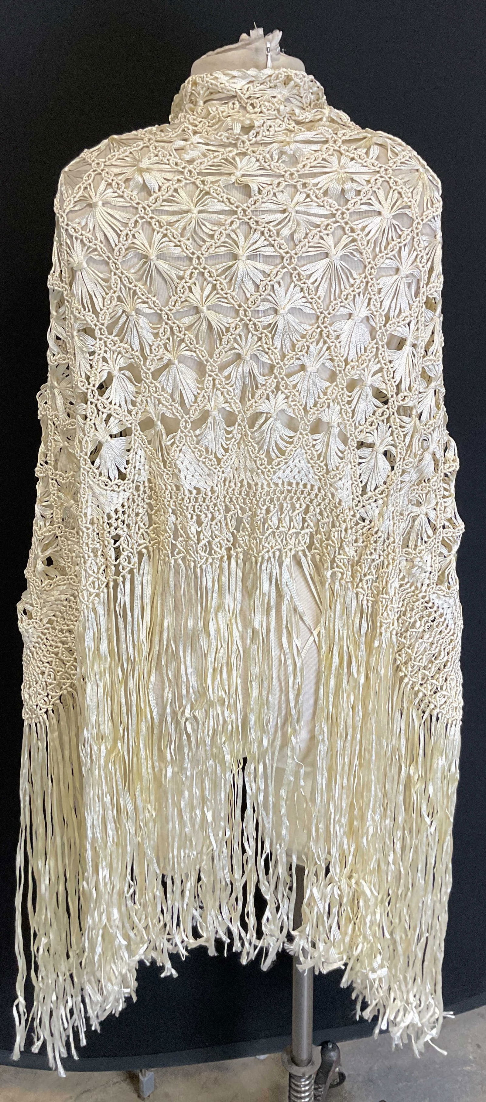 Vintage White Stitched Fringed Shawl: Vintage white stitched fringed shawl. Feels like silk. White fringed trim. Stitched floral motifs in a diamond like pattern. Accented stitching surrounding pattern. Measures approx 36 x 55 inches. Wea