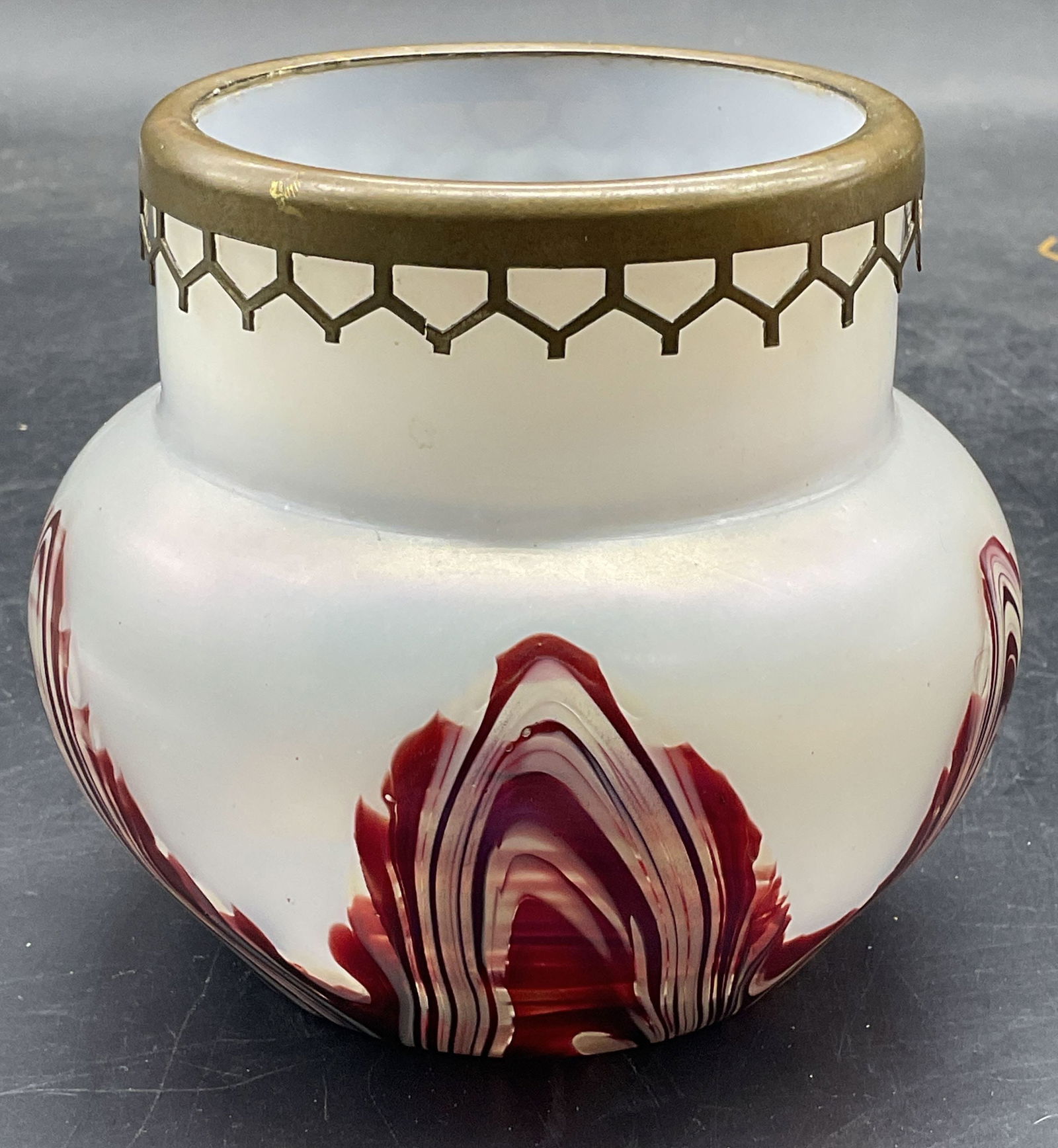 Art Nouveau Style Iridescent Red White Glass Vase: Art nouveau style hand blown art glass vase. Iridescent white with red feather pull design. Bulb shaped bowl. Brass rim cover. Measures approx 4.25 x 4 inches. Some scratching. Art glass vase, art nou